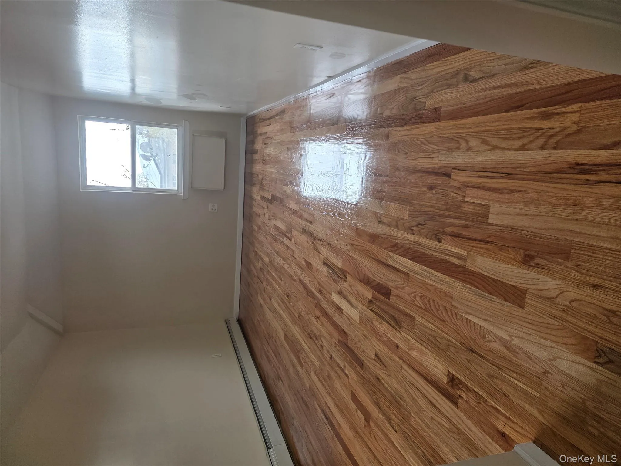 Spare room with light wood-type flooring, baseboard heating, and vaulted ceiling Spare room with light wood-type flooring, baseboard heating, and vaulted ceiling