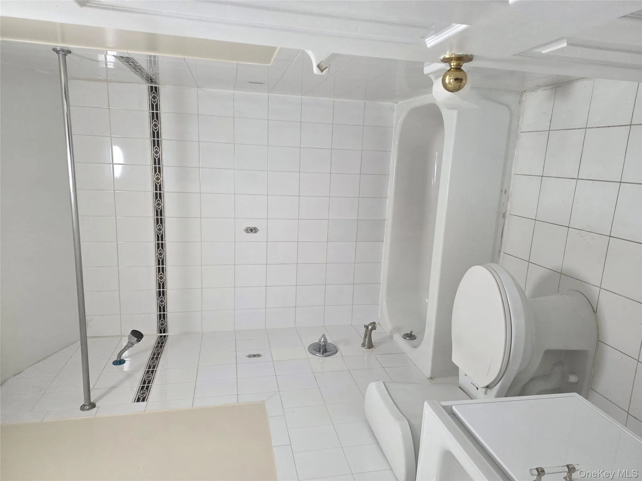 Bathroom with light tile patterned floors, bathtub / shower combination, tile walls, and vanity Bathroom with light tile patterned floors, bathtub / shower combination, tile walls, and vanity