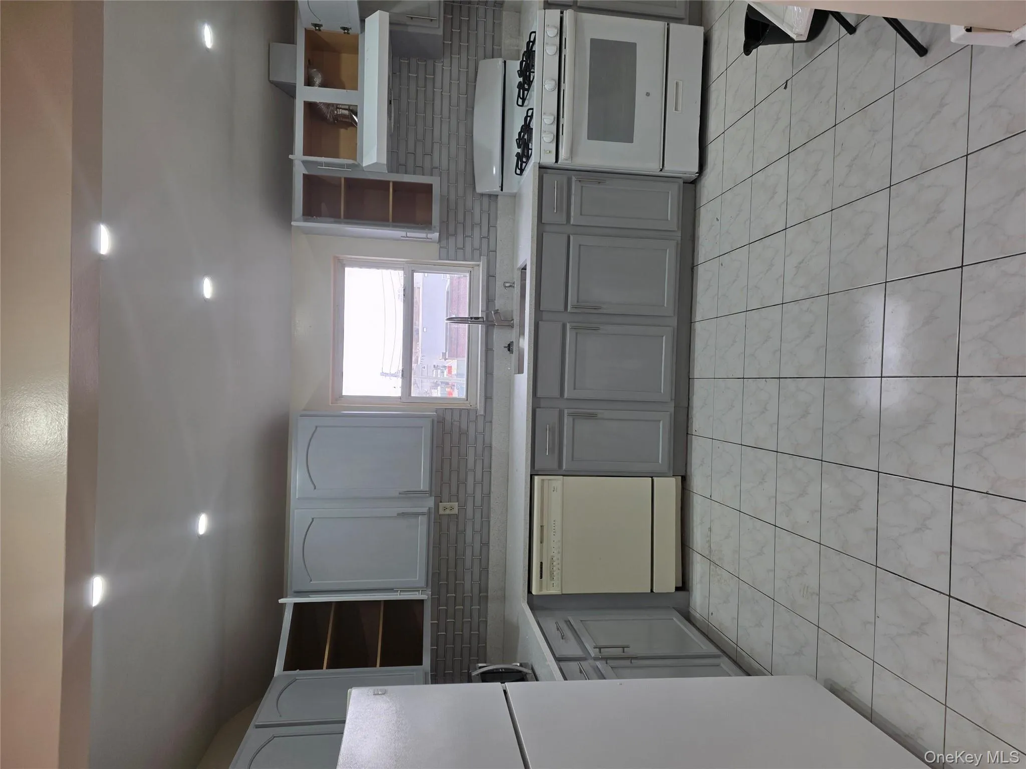 Kitchen with gray cabinets, stove, refrigerator, dishwashing machine, and recessed lighting Kitchen with gray cabinets, stove, refrigerator, dishwashing machine, and recessed lighting