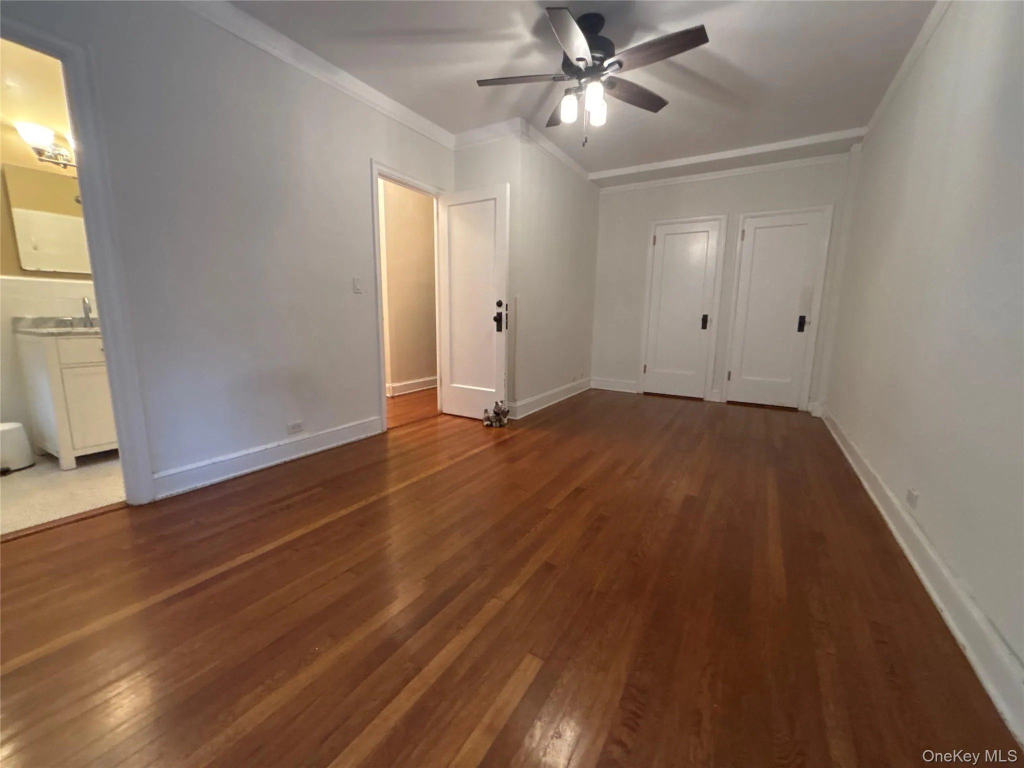 Unfurnished bedroom with crown molding, dark wood finished floors, and ceiling fan Unfurnished bedroom with crown molding, dark wood finished floors, and ceiling fan