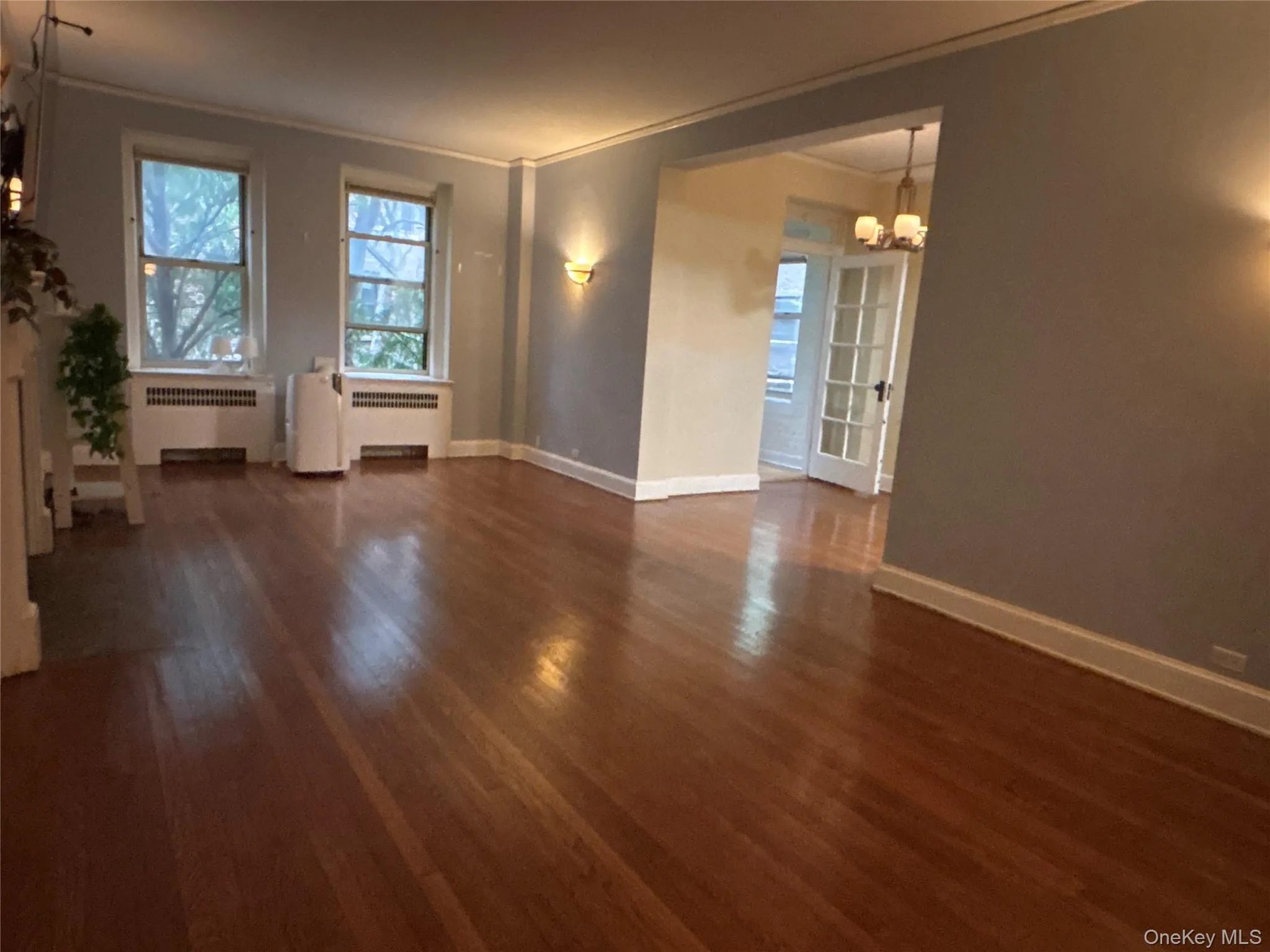 Unfurnished room with a chandelier, ornamental molding, dark wood-type flooring, and radiator heating unit Unfurnished room with a chandelier, ornamental molding, dark wood-type flooring, and radiator heating unit