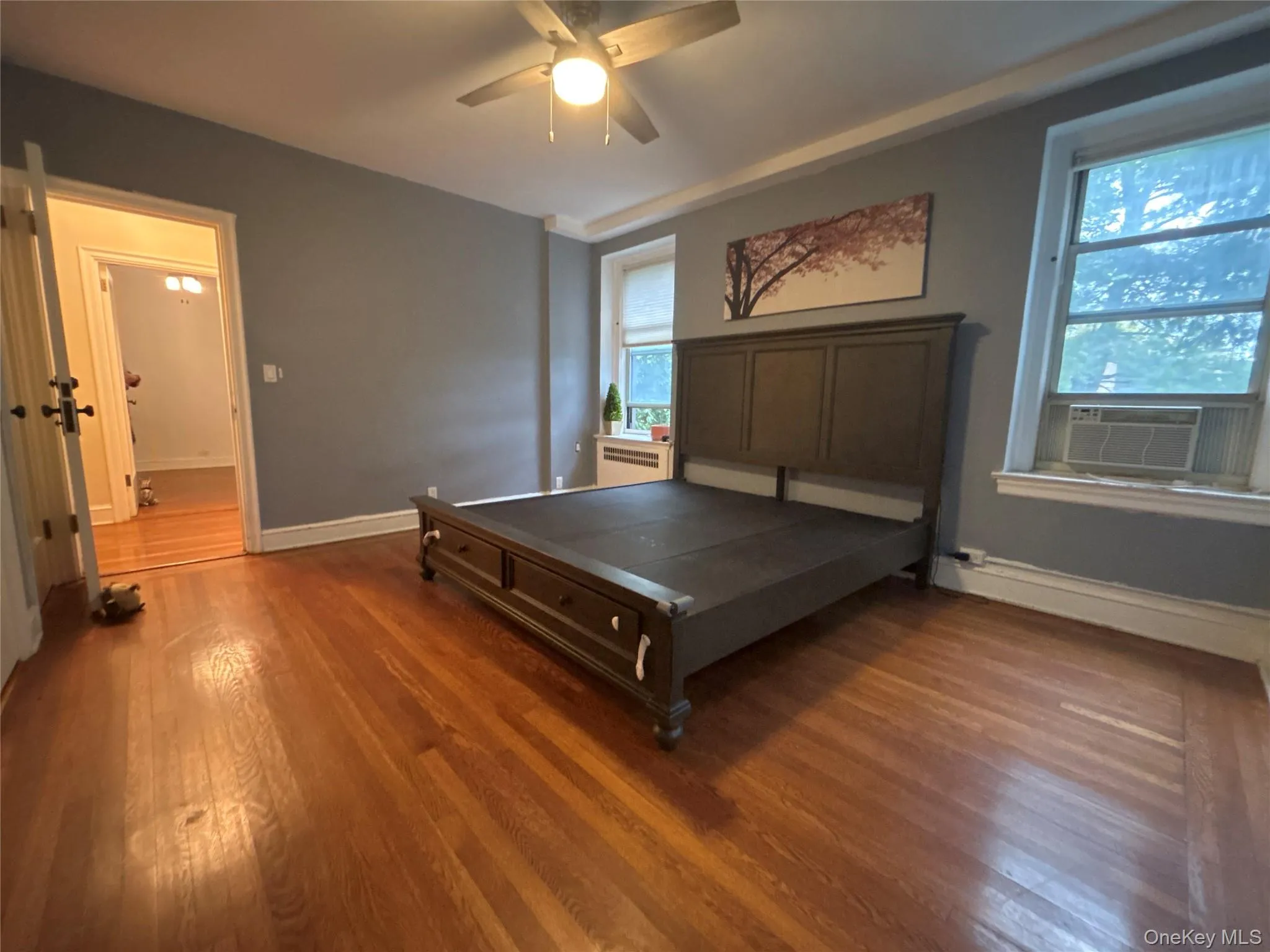 Bedroom with wood finished floors, ceiling fan, and cooling unit Bedroom with wood finished floors, ceiling fan, and cooling unit