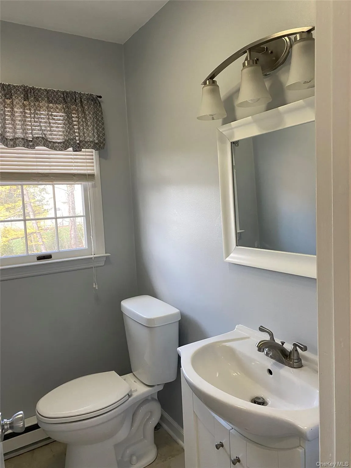 Half bath featuring vanity and a baseboard heating unit Half bath featuring vanity and a baseboard heating unit