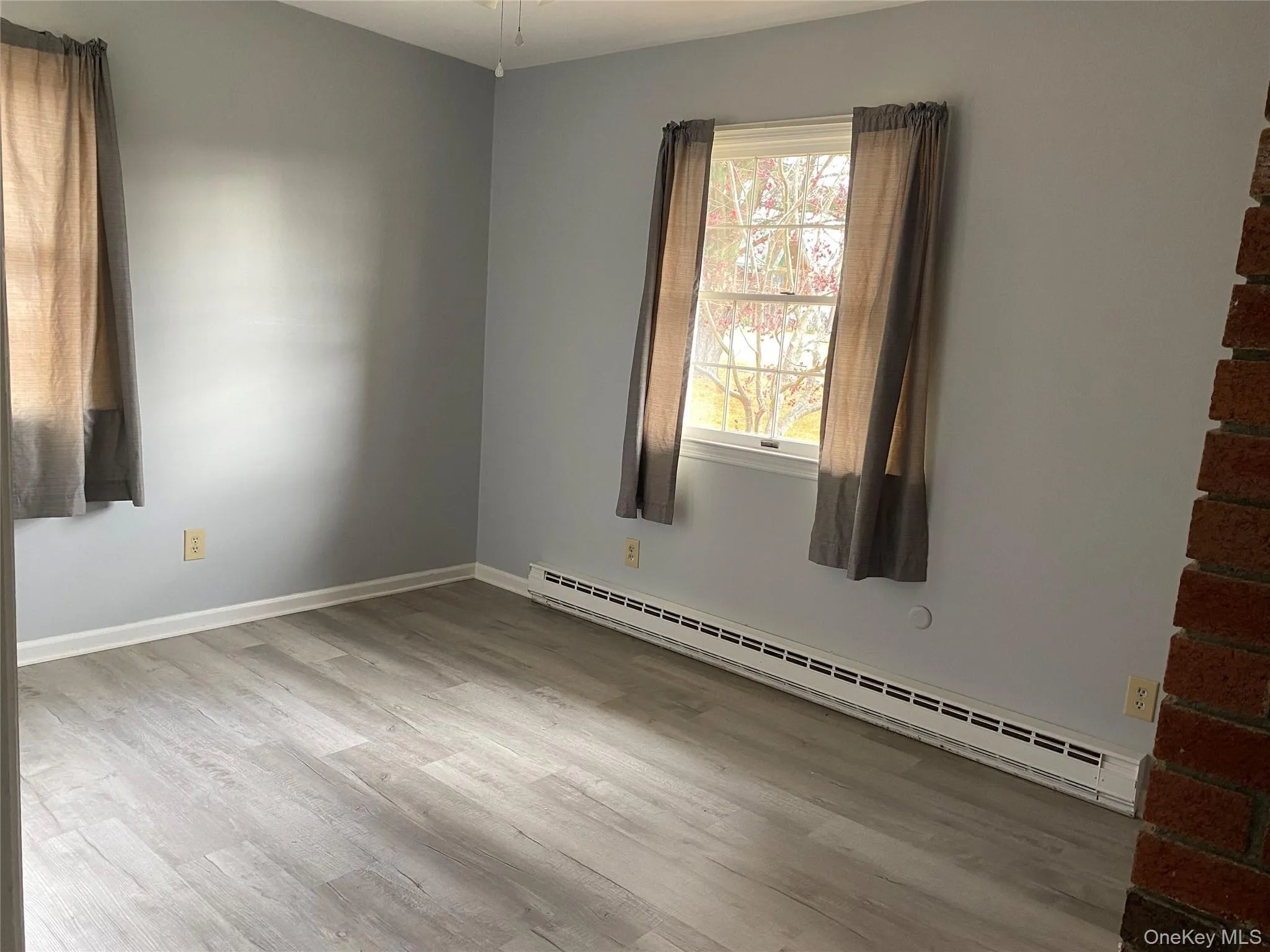 Unfurnished room with a baseboard radiator and light wood-type flooring Unfurnished room with a baseboard radiator and light wood-type flooring