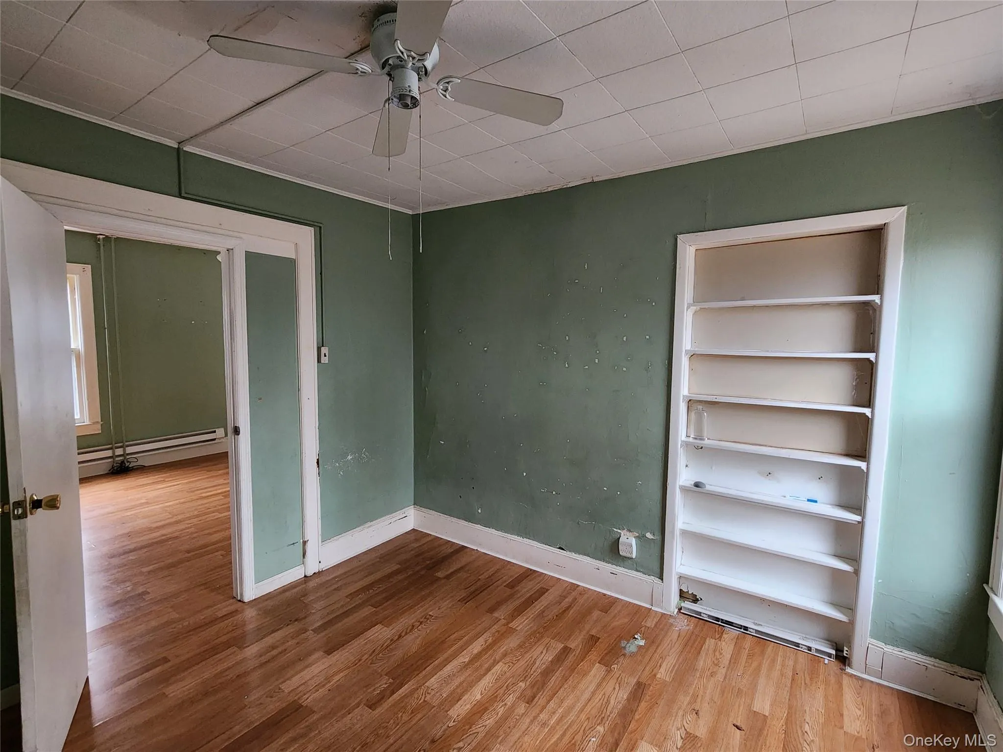 Unfurnished bedroom featuring wood finished floors, baseboard heating, and ceiling fan Unfurnished bedroom featuring wood finished floors, baseboard heating, and ceiling fan