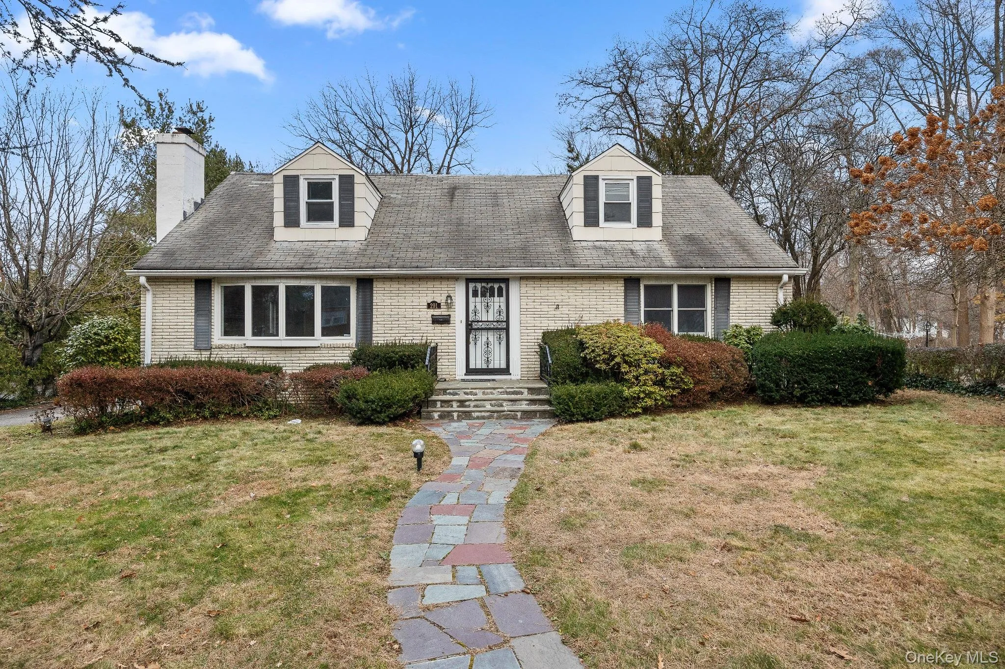 Cape cod house featuring brick siding, a chimney, and a front yard Cape cod house featuring brick siding, a chimney, and a front yard