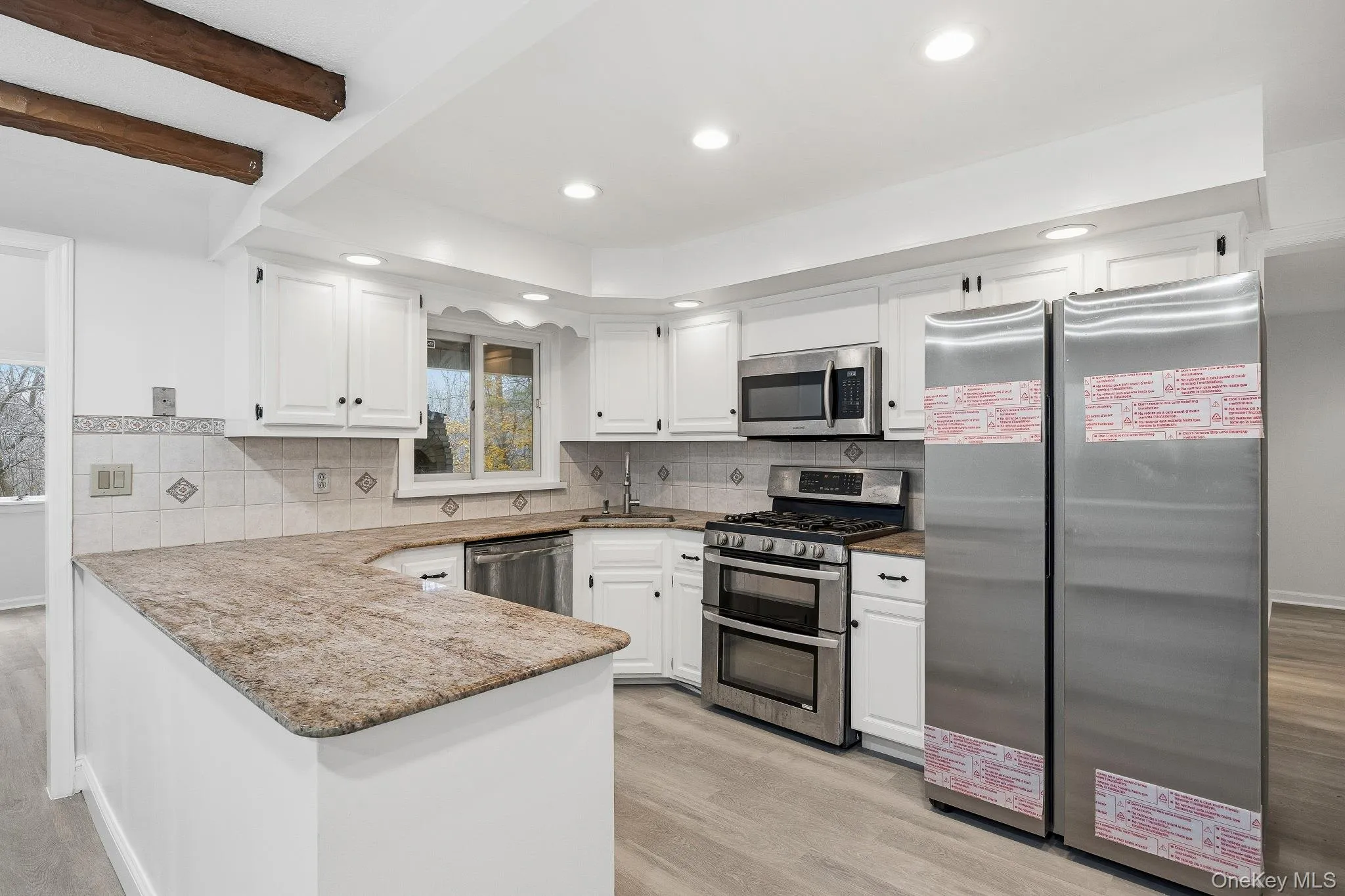 Kitchen featuring appliances with stainless steel finishes, light wood-style flooring, white cabinetry, and recessed lighting Kitchen featuring appliances with stainless steel finishes, light wood-style flooring, white cabinetry, and recessed lighting