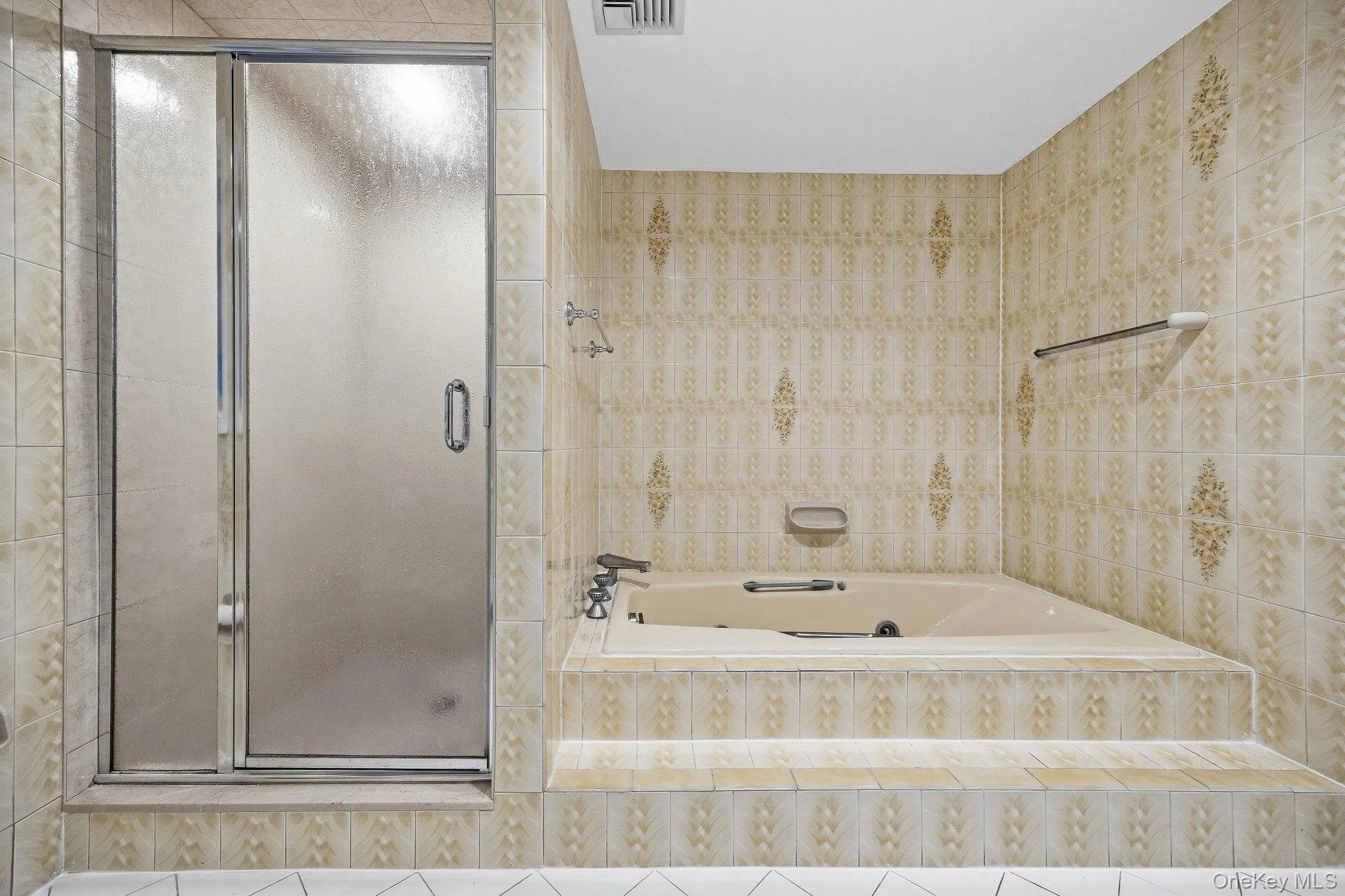 Full bathroom with a stall shower, a garden tub, and tile walls Full bathroom with a stall shower, a garden tub, and tile walls