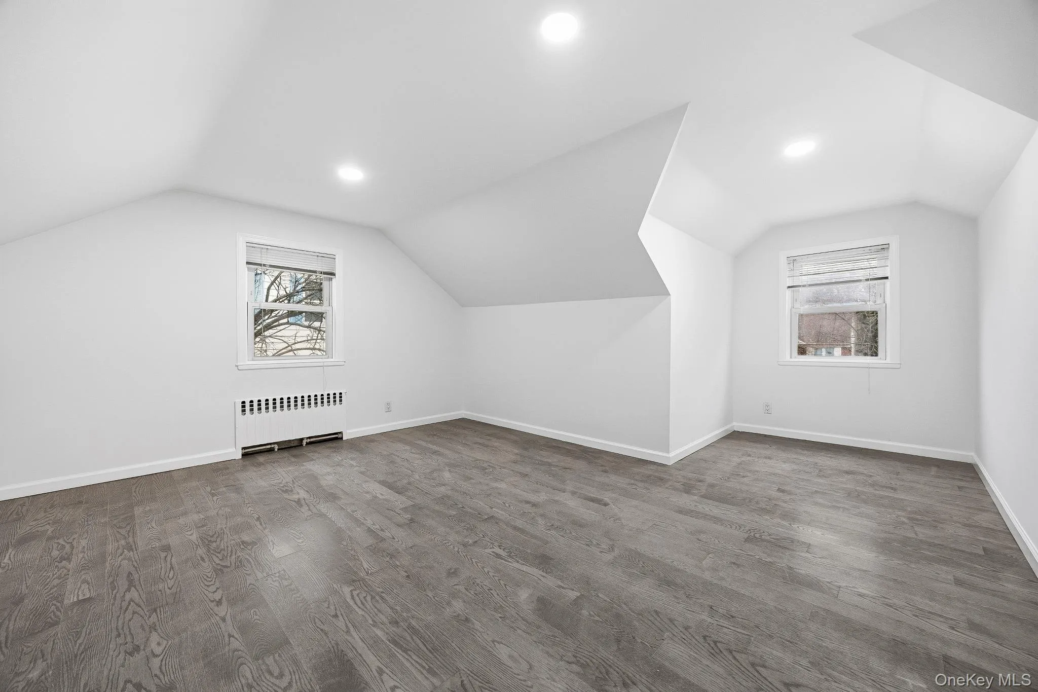 Additional living space with lofted ceiling, wood finished floors, radiator heating unit, and recessed lighting Additional living space with lofted ceiling, wood finished floors, radiator heating unit, and recessed lighting