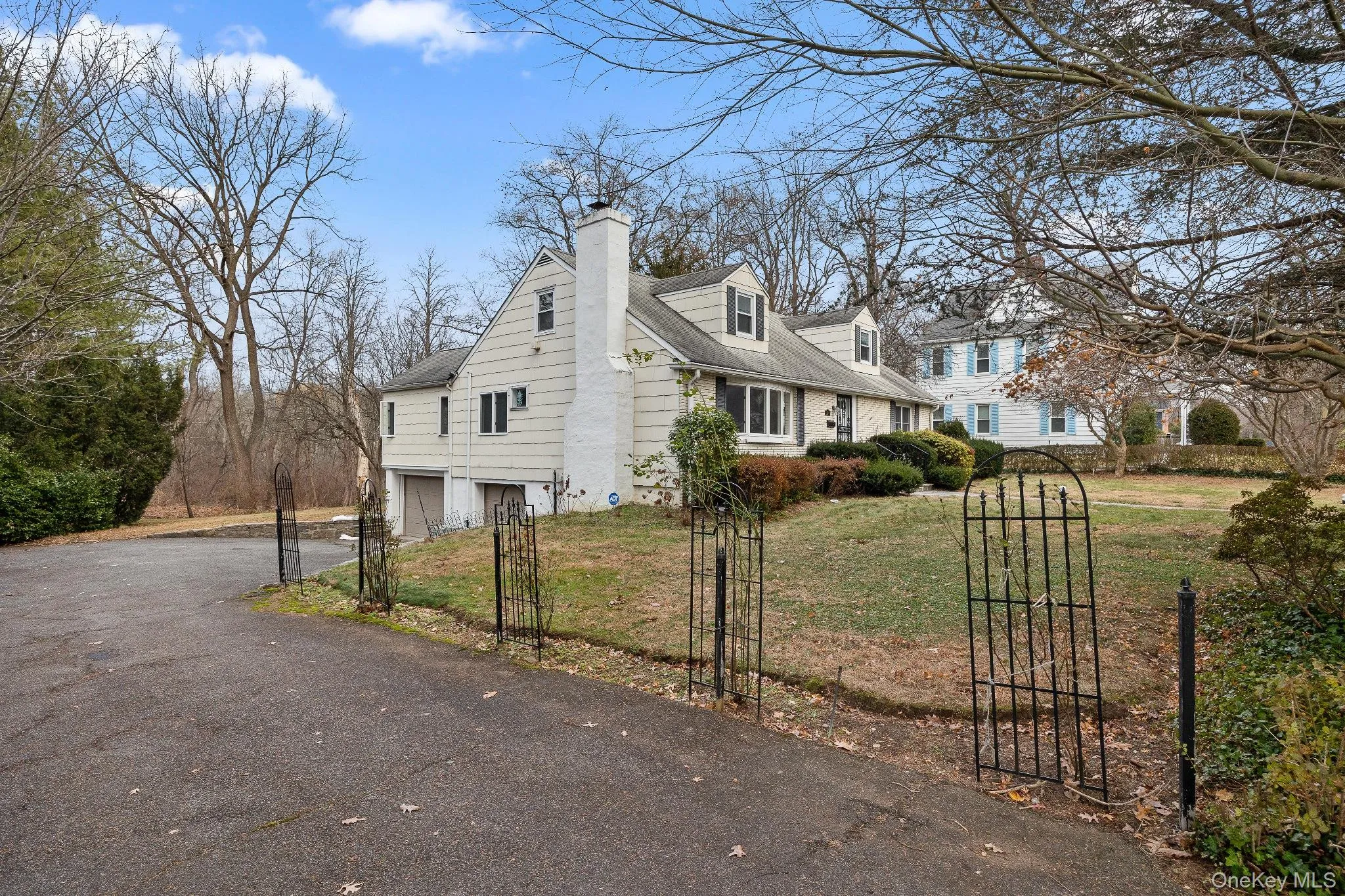 View of side of property featuring driveway, an attached garage, a chimney, and a gate View of side of property featuring driveway, an attached garage, a chimney, and a gate