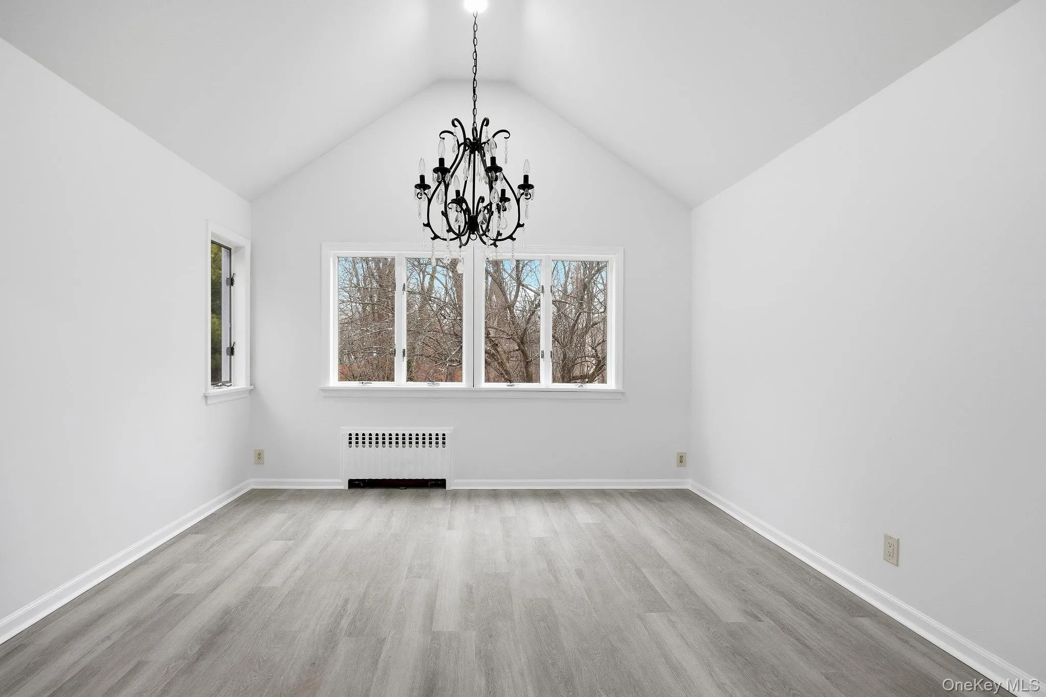 Unfurnished dining area with light wood finished floors, radiator heating unit, a chandelier, and lofted ceiling Unfurnished dining area with light wood finished floors, radiator heating unit, a chandelier, and lofted ceiling