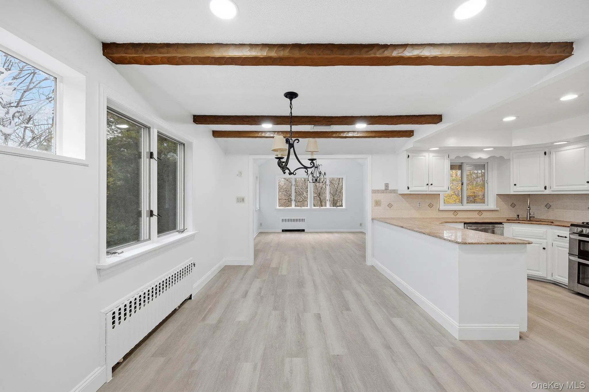 Kitchen with white cabinetry, radiator heating unit, tasteful backsplash, recessed lighting, and a peninsula Kitchen with white cabinetry, radiator heating unit, tasteful backsplash, recessed lighting, and a peninsula