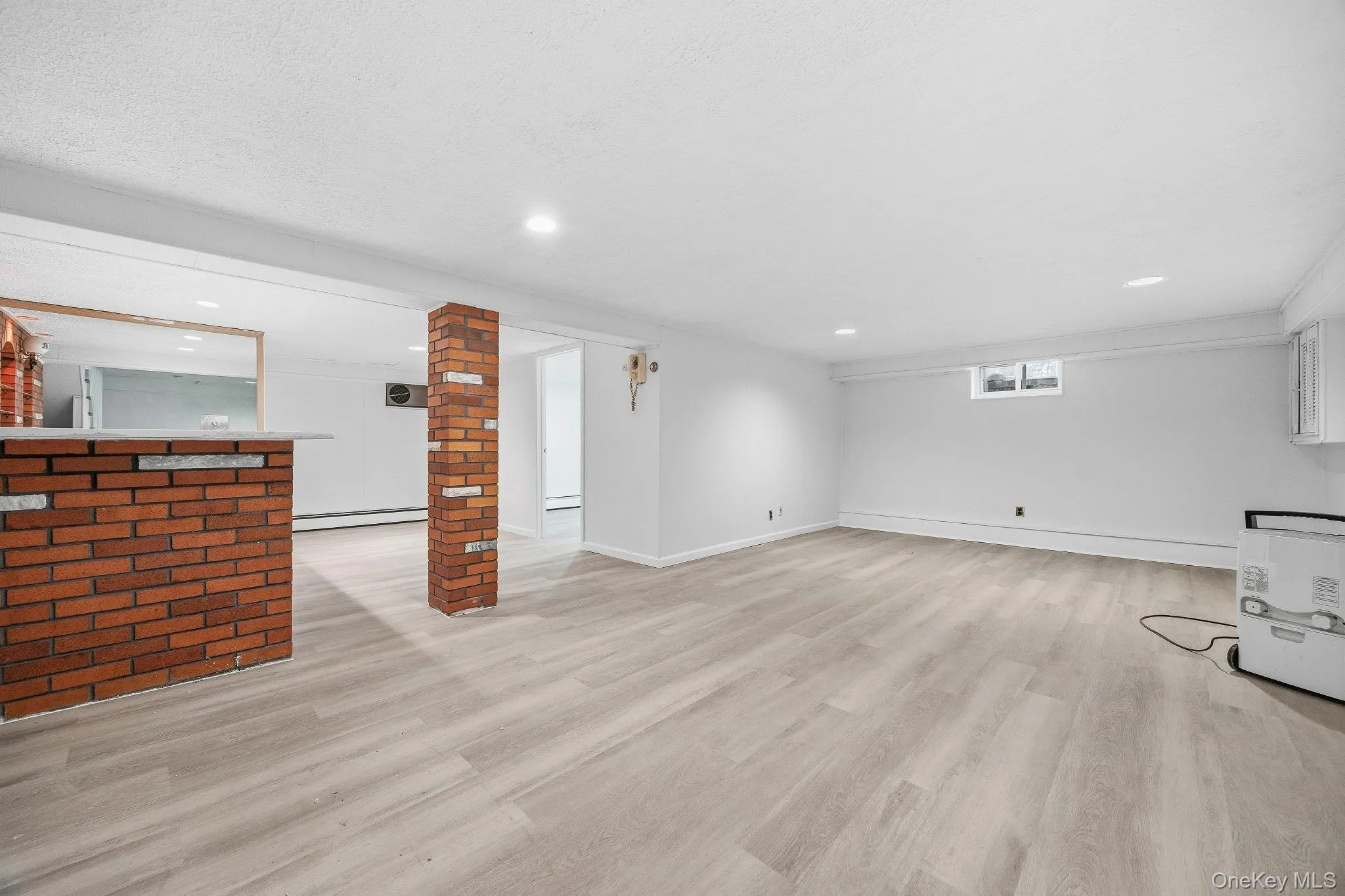 Unfurnished living room featuring light wood-style floors and baseboard heating Unfurnished living room featuring light wood-style floors and baseboard heating