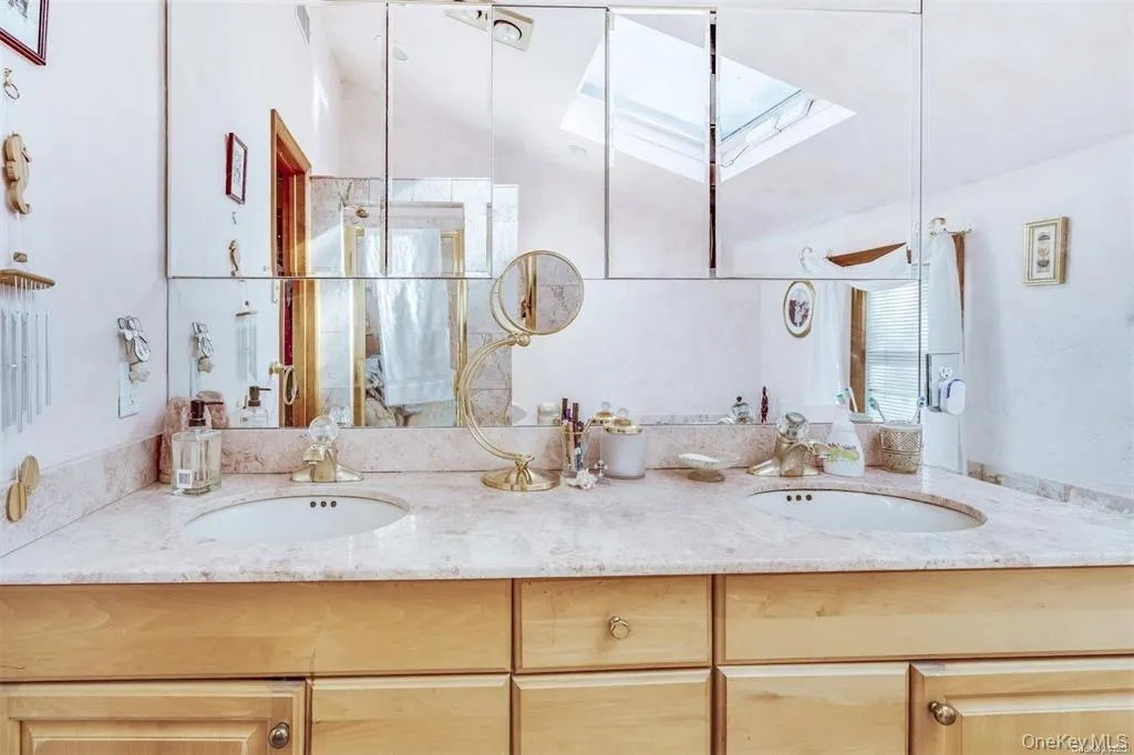 Bathroom featuring a skylight, double vanity, and healthy amount of natural light Bathroom featuring a skylight, double vanity, and healthy amount of natural light
