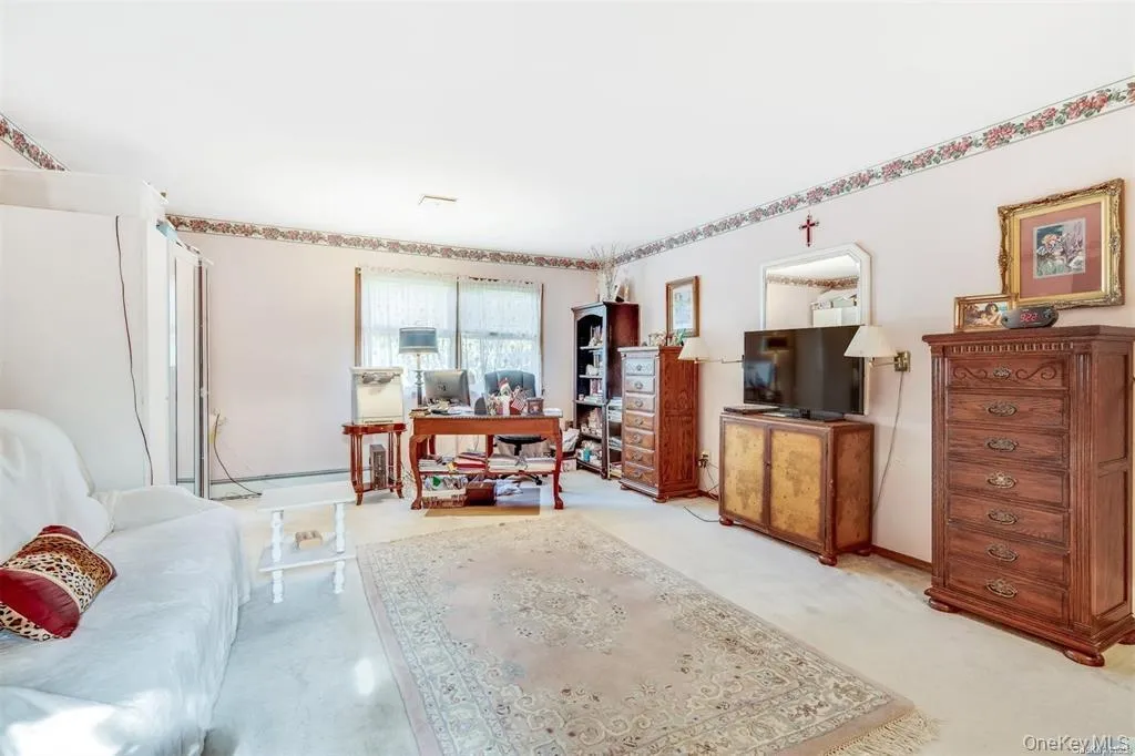 Carpeted living room with a desk and baseboards Carpeted living room with a desk and baseboards
