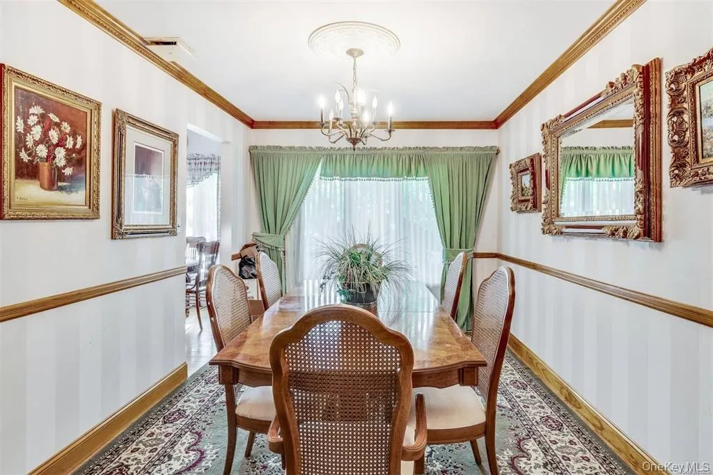 Dining area featuring plenty of natural light, crown molding, wallpapered walls, and a chandelier Dining area featuring plenty of natural light, crown molding, wallpapered walls, and a chandelier