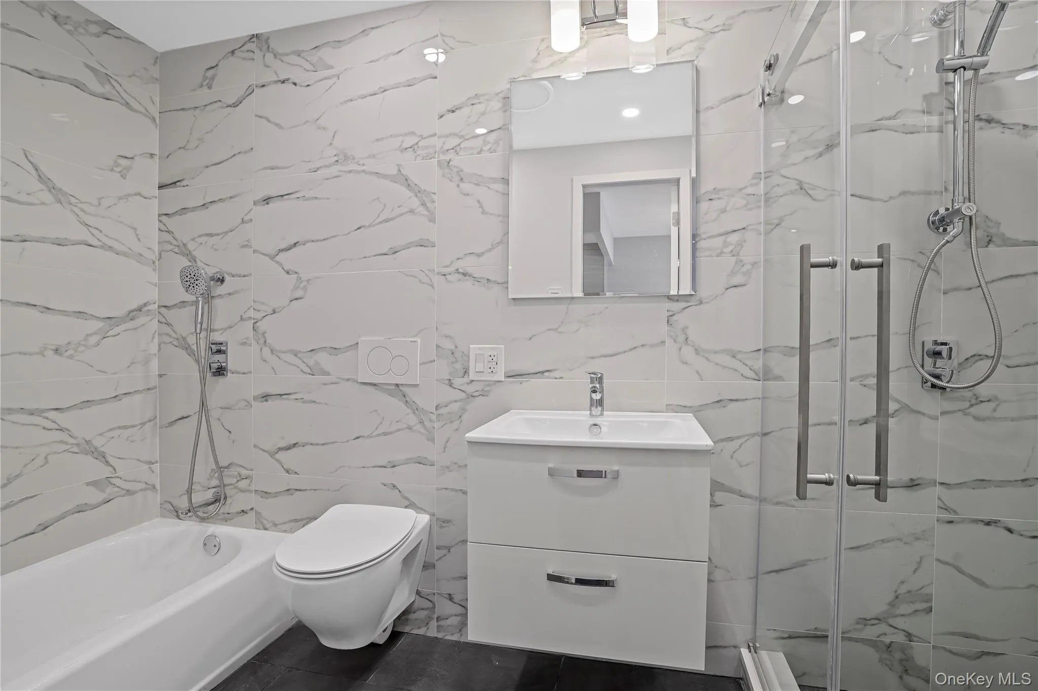 Full bathroom featuring a marble finish shower, vanity, and tile walls Full bathroom featuring a marble finish shower, vanity, and tile walls