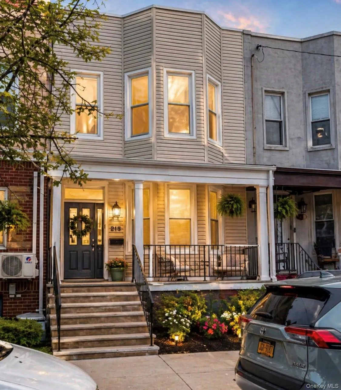 Inviting facade featuring a columned front porch, bay windows, and a dark entry door Inviting facade featuring a columned front porch, bay windows, and a dark entry door