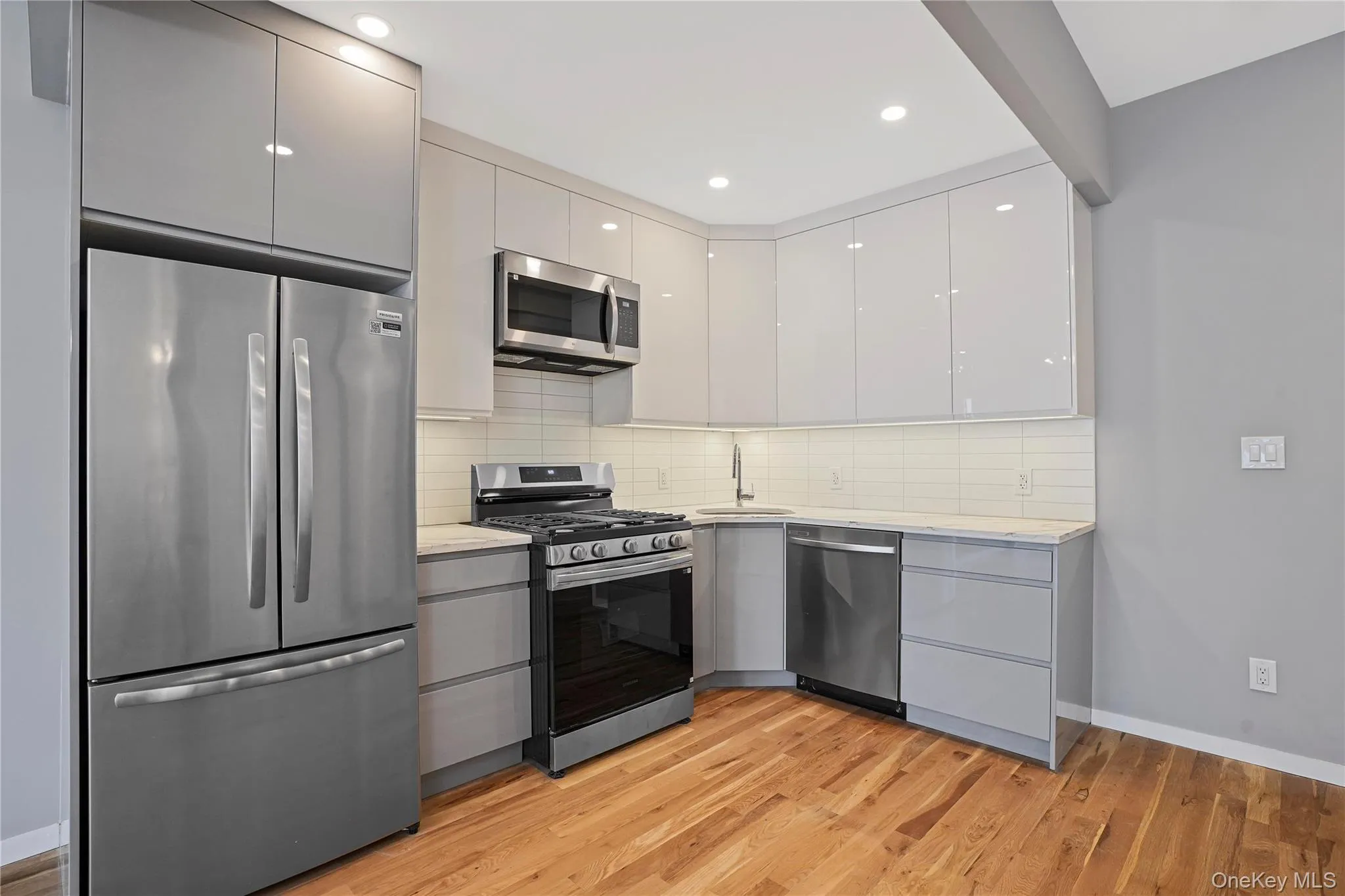 Kitchen with appliances with stainless steel finishes, modern cabinets, decorative backsplash, light wood-style flooring, and recessed lighting Kitchen with appliances with stainless steel finishes, modern cabinets, decorative backsplash, light wood-style flooring, and recessed lighting