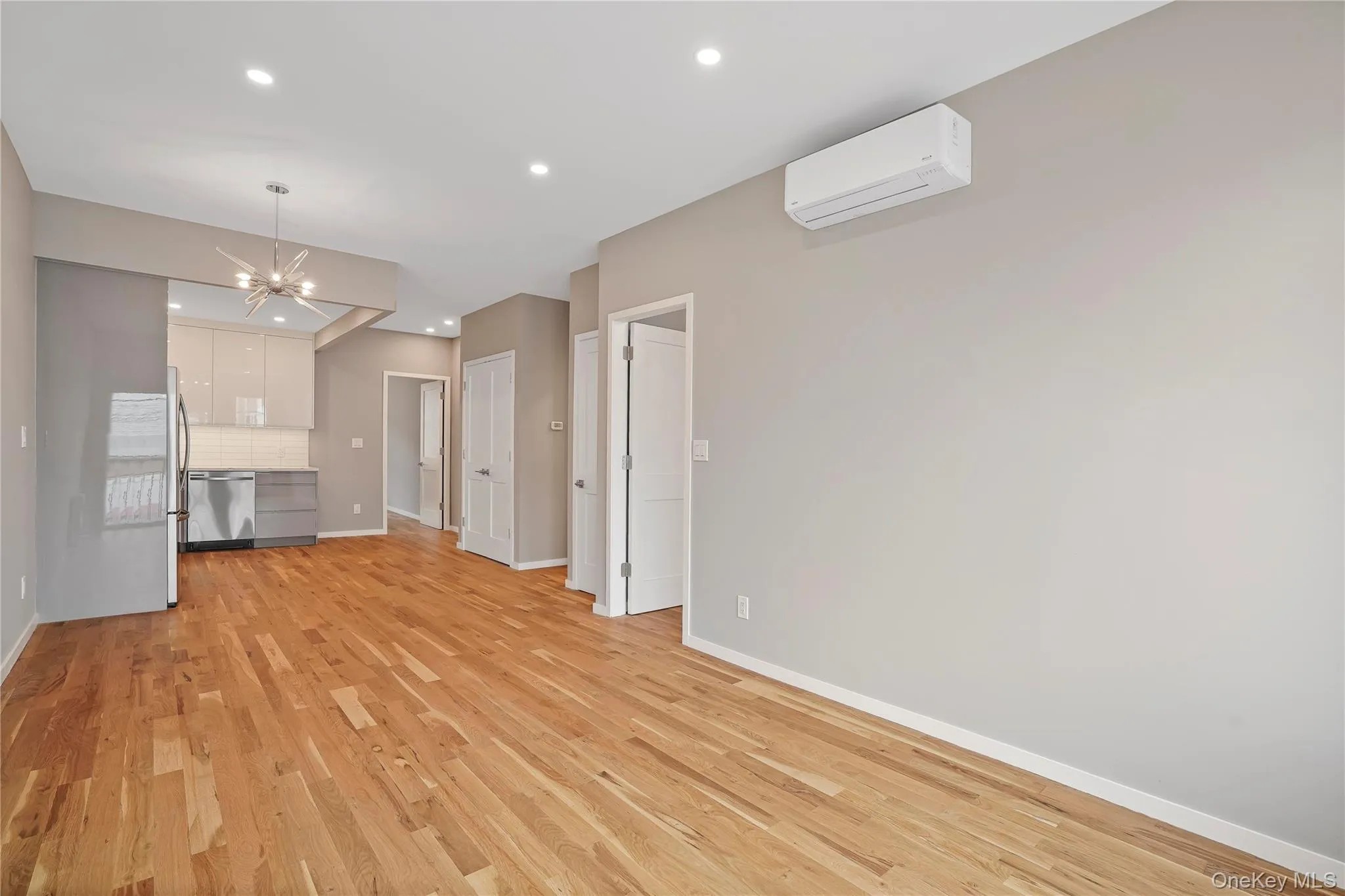 Unfurnished living room featuring a chandelier, light wood-type flooring, recessed lighting, and a wall mounted AC Unfurnished living room featuring a chandelier, light wood-type flooring, recessed lighting, and a wall mounted AC