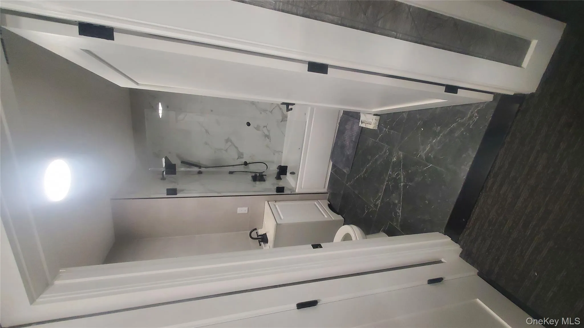 Bathroom featuring vanity, a combined bath / shower with marble appearance, and dark marble finish flooring Bathroom featuring vanity, a combined bath / shower with marble appearance, and dark marble finish flooring