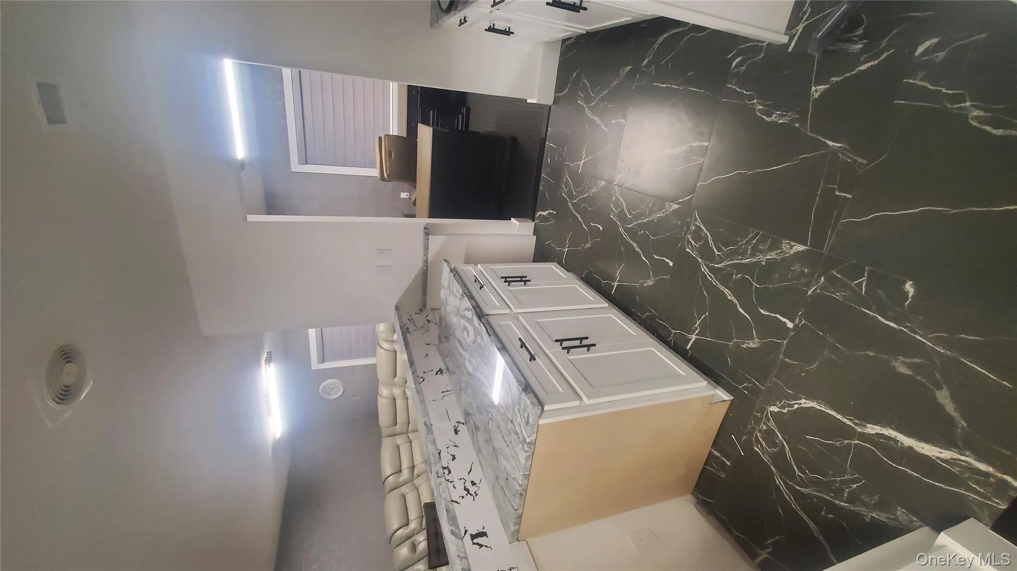 Kitchen with dark marble finish floors, white cabinetry, light stone countertops, and a peninsula Kitchen with dark marble finish floors, white cabinetry, light stone countertops, and a peninsula