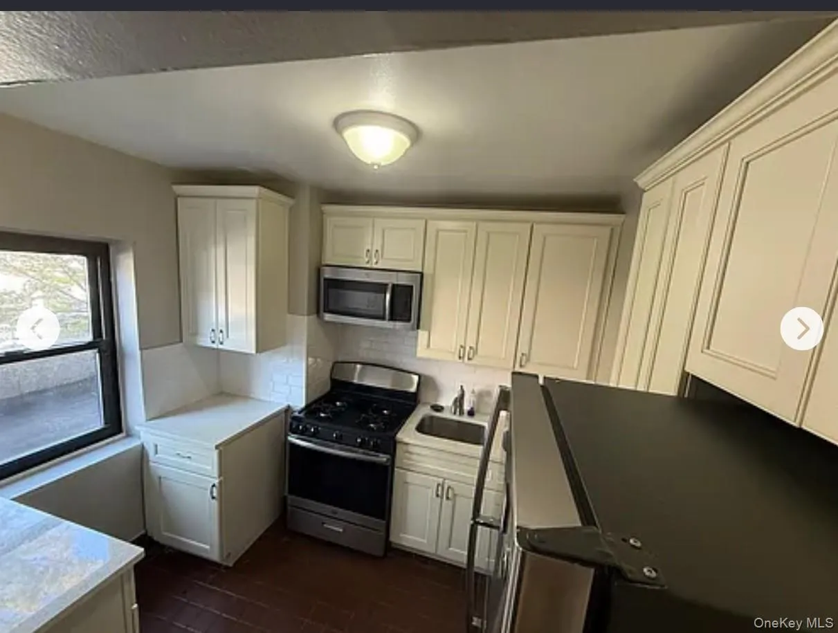 Kitchen with stainless steel appliances, backsplash, white cabinets, and dark wood-type flooring Kitchen with stainless steel appliances, backsplash, white cabinets, and dark wood-type flooring