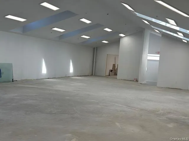 Spare room with unfinished concrete flooring and high vaulted ceiling Spare room with unfinished concrete flooring and high vaulted ceiling