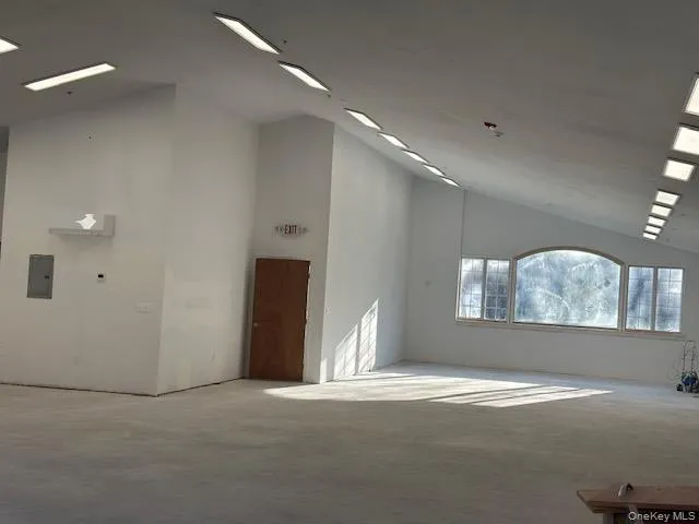 Unfurnished room with high vaulted ceiling and electric panel Unfurnished room with high vaulted ceiling and electric panel