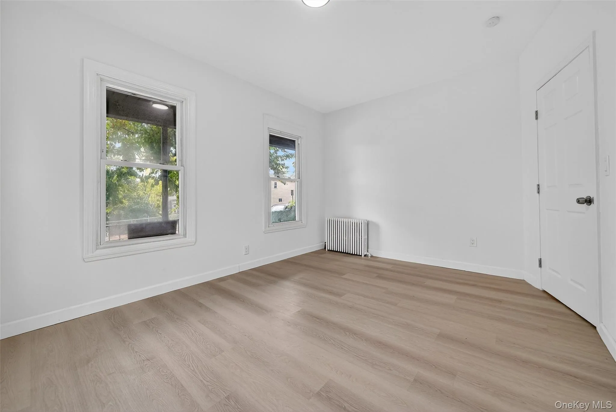 Empty room with light wood-style flooring, radiator heating unit, and recessed lighting Empty room with light wood-style flooring, radiator heating unit, and recessed lighting