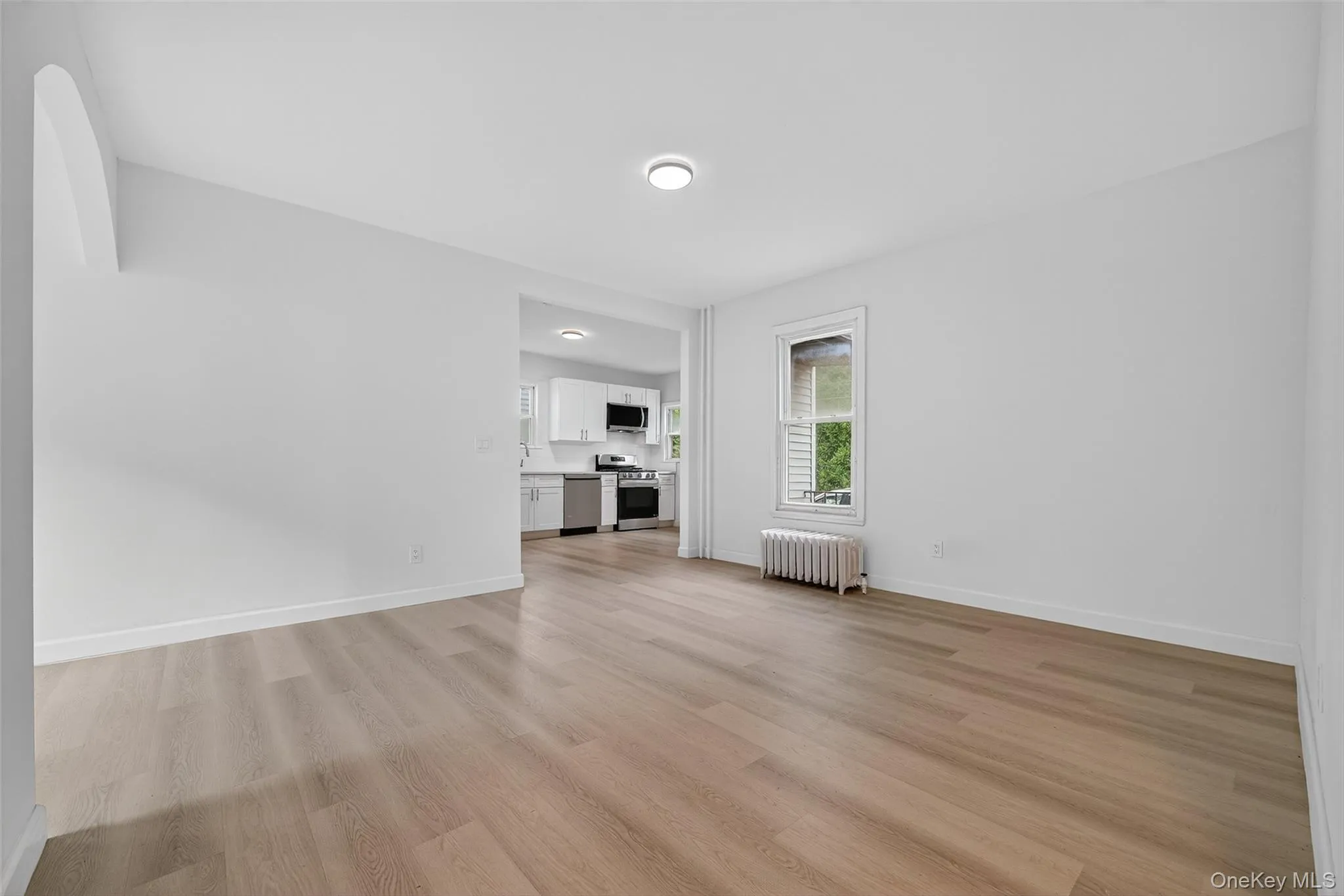 Unfurnished living room with light wood-style floors and radiator heating unit Unfurnished living room with light wood-style floors and radiator heating unit