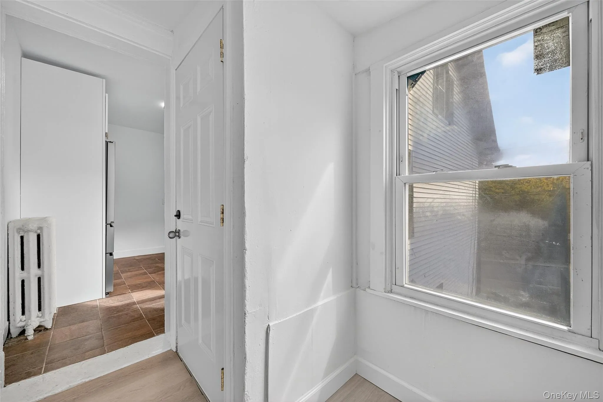 Hall featuring radiator and light wood finished floors Hall featuring radiator and light wood finished floors