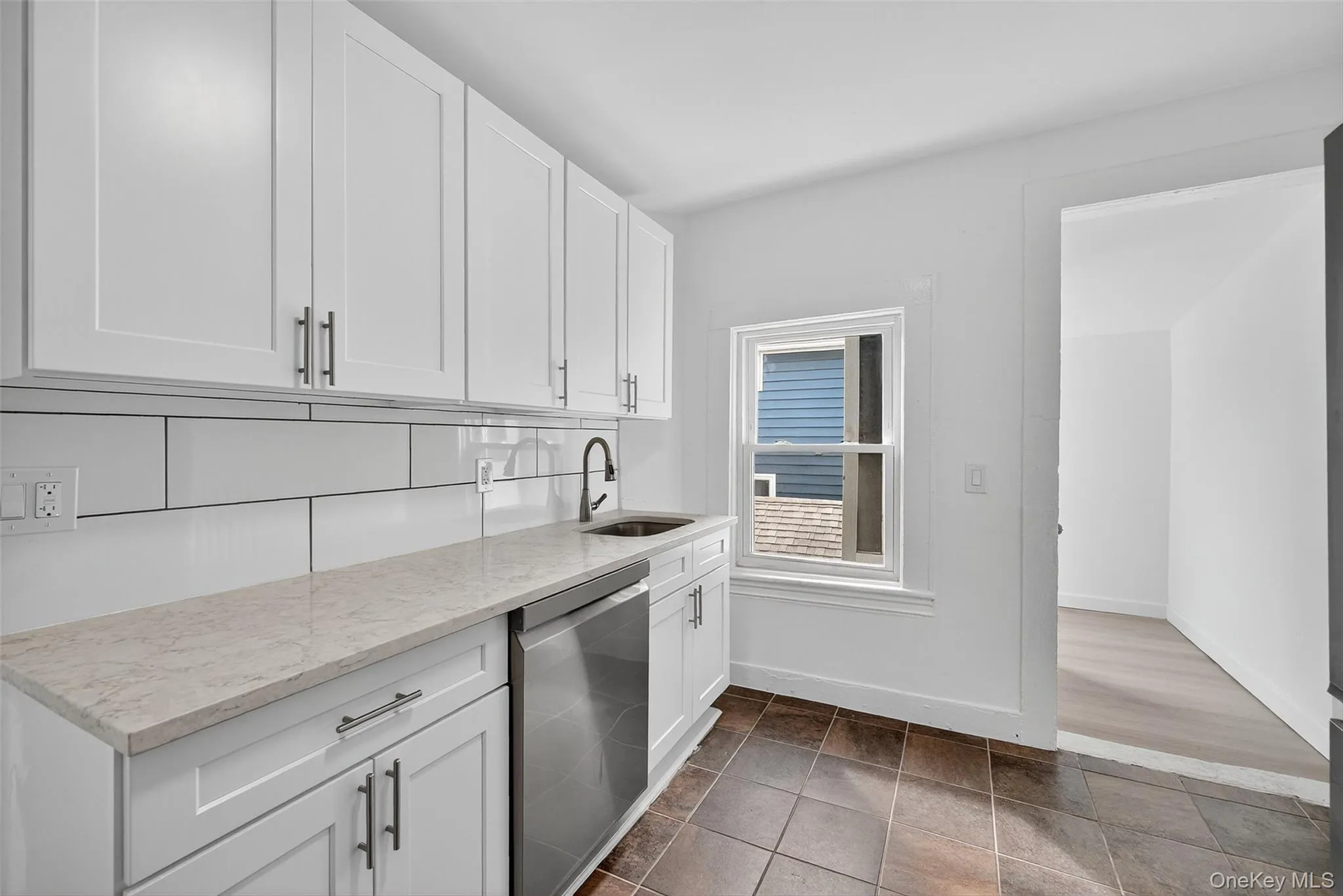 Kitchen featuring white cabinetry, light stone counters, and stainless steel dishwasher Kitchen featuring white cabinetry, light stone counters, and stainless steel dishwasher