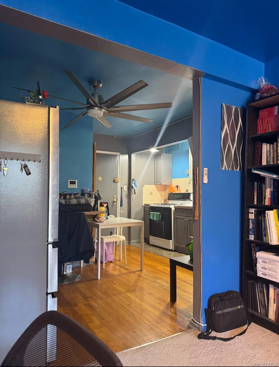 Kitchen featuring freestanding refrigerator, range with gas stovetop, light wood-type flooring, ceiling fan, and light countertops Kitchen featuring freestanding refrigerator, range with gas stovetop, light wood-type flooring, ceiling fan, and light countertops