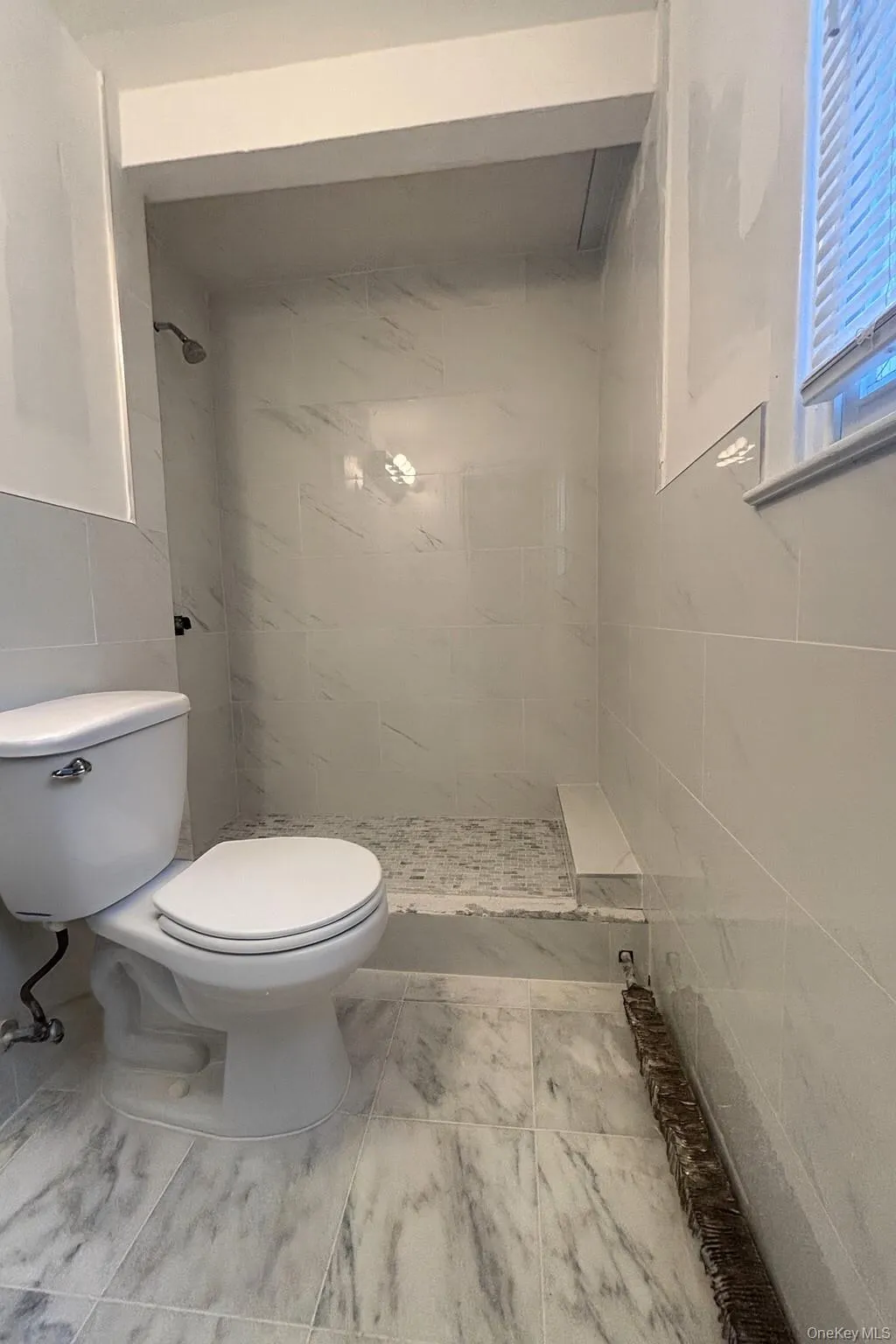 Bathroom featuring a stall shower and tile walls Bathroom featuring a stall shower and tile walls