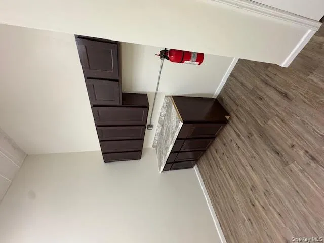 Kitchen featuring dark brown cabinets, dark wood-style flooring, and light countertops Kitchen featuring dark brown cabinets, dark wood-style flooring, and light countertops