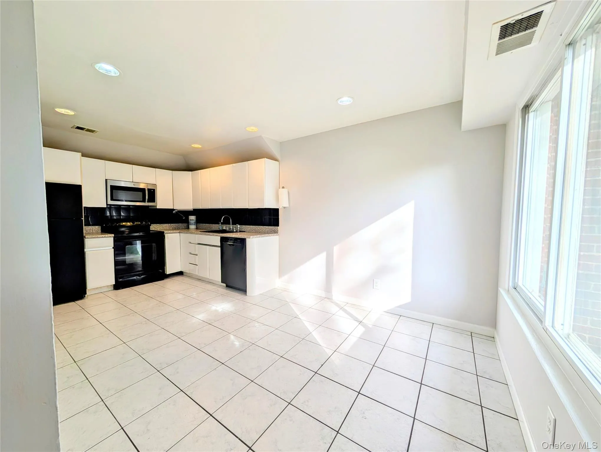 Kitchen featuring light tile patterned floors, white cabinetry, black appliances, tasteful backsplash, and recessed lighting Kitchen featuring light tile patterned floors, white cabinetry, black appliances, tasteful backsplash, and recessed lighting