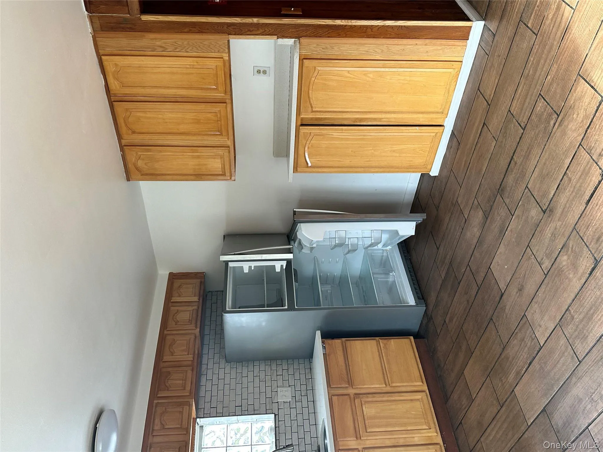Kitchen with dark wood-style floors, refrigerator, decorative backsplash, and brown cabinets Kitchen with dark wood-style floors, refrigerator, decorative backsplash, and brown cabinets