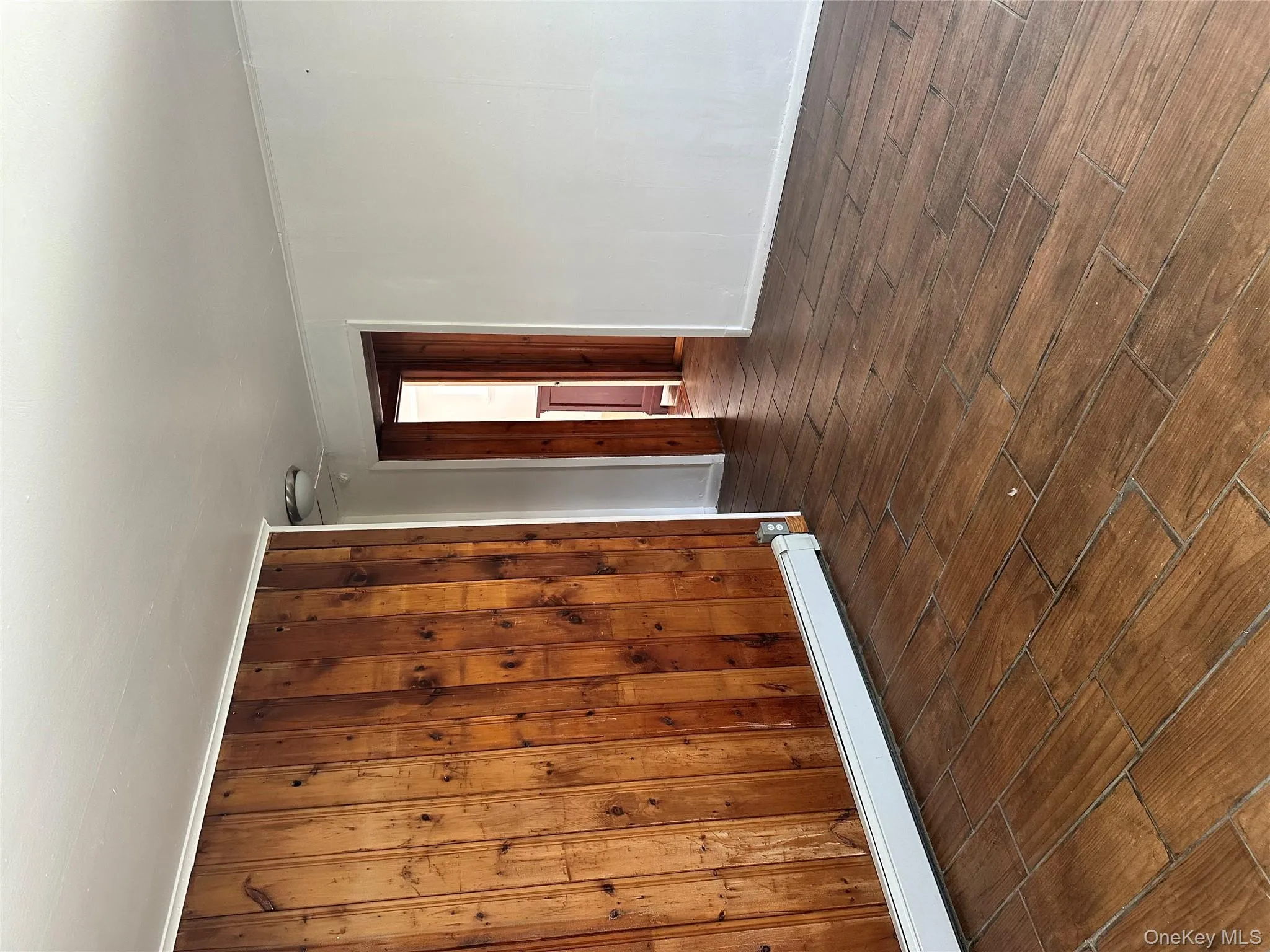 Unfurnished room with baseboard heating, dark wood-style flooring, and wooden walls Unfurnished room with baseboard heating, dark wood-style flooring, and wooden walls