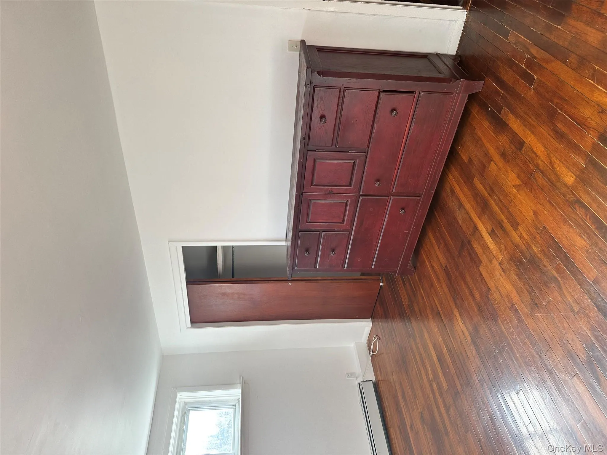 Unfurnished bedroom with dark wood-style floors, a baseboard heating unit, and a closet Unfurnished bedroom with dark wood-style floors, a baseboard heating unit, and a closet