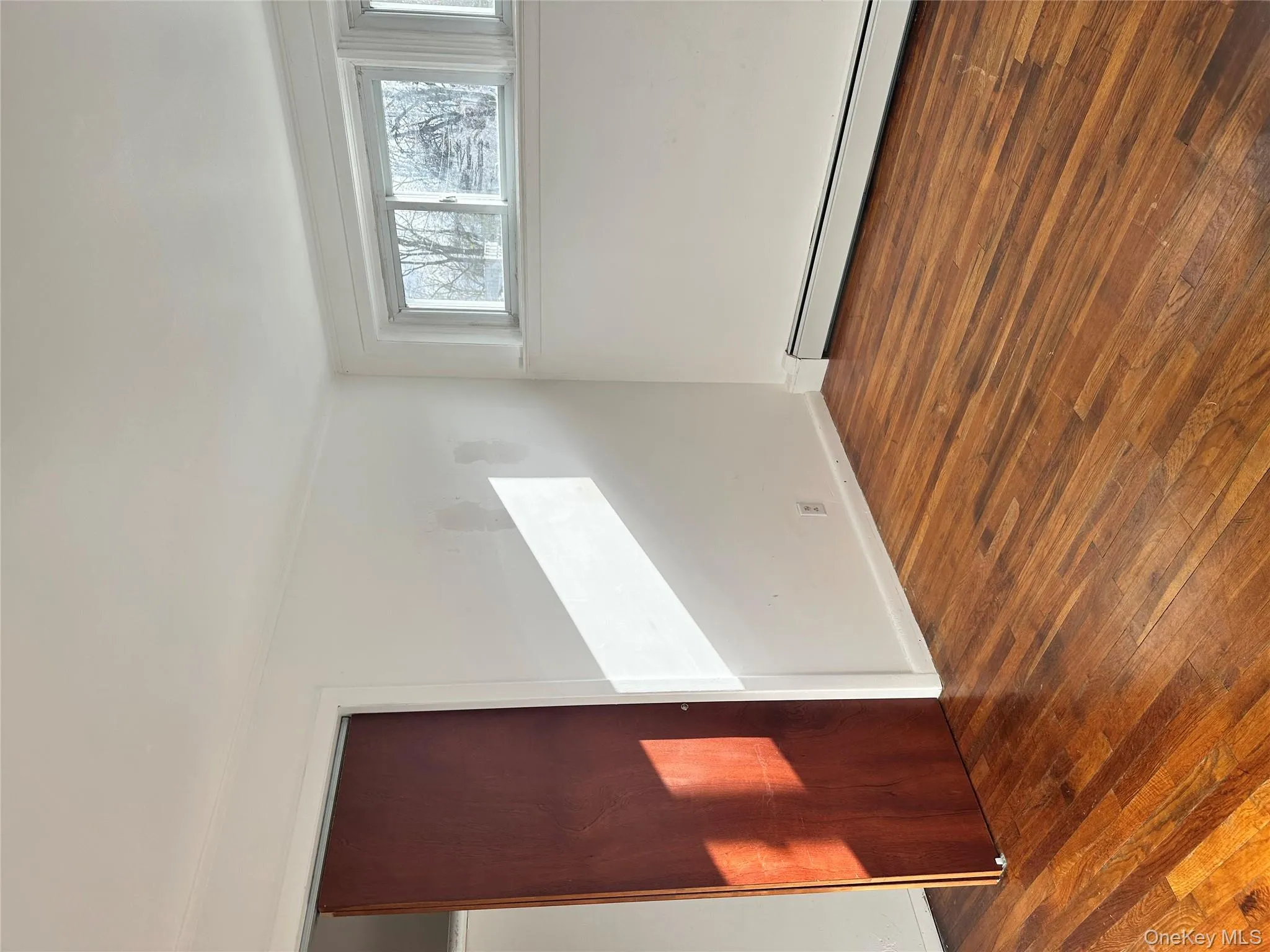 Empty room with baseboard heating and dark wood finished floors Empty room with baseboard heating and dark wood finished floors