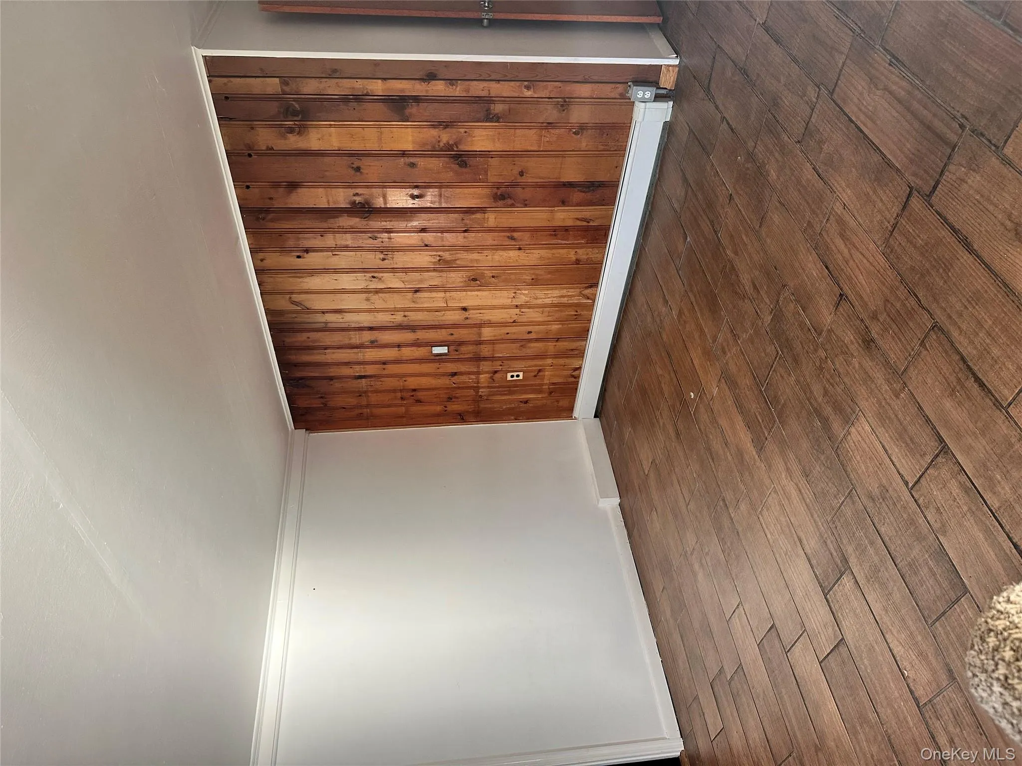 Empty room with wood walls, a baseboard radiator, dark wood-style floors, and crown molding Empty room with wood walls, a baseboard radiator, dark wood-style floors, and crown molding