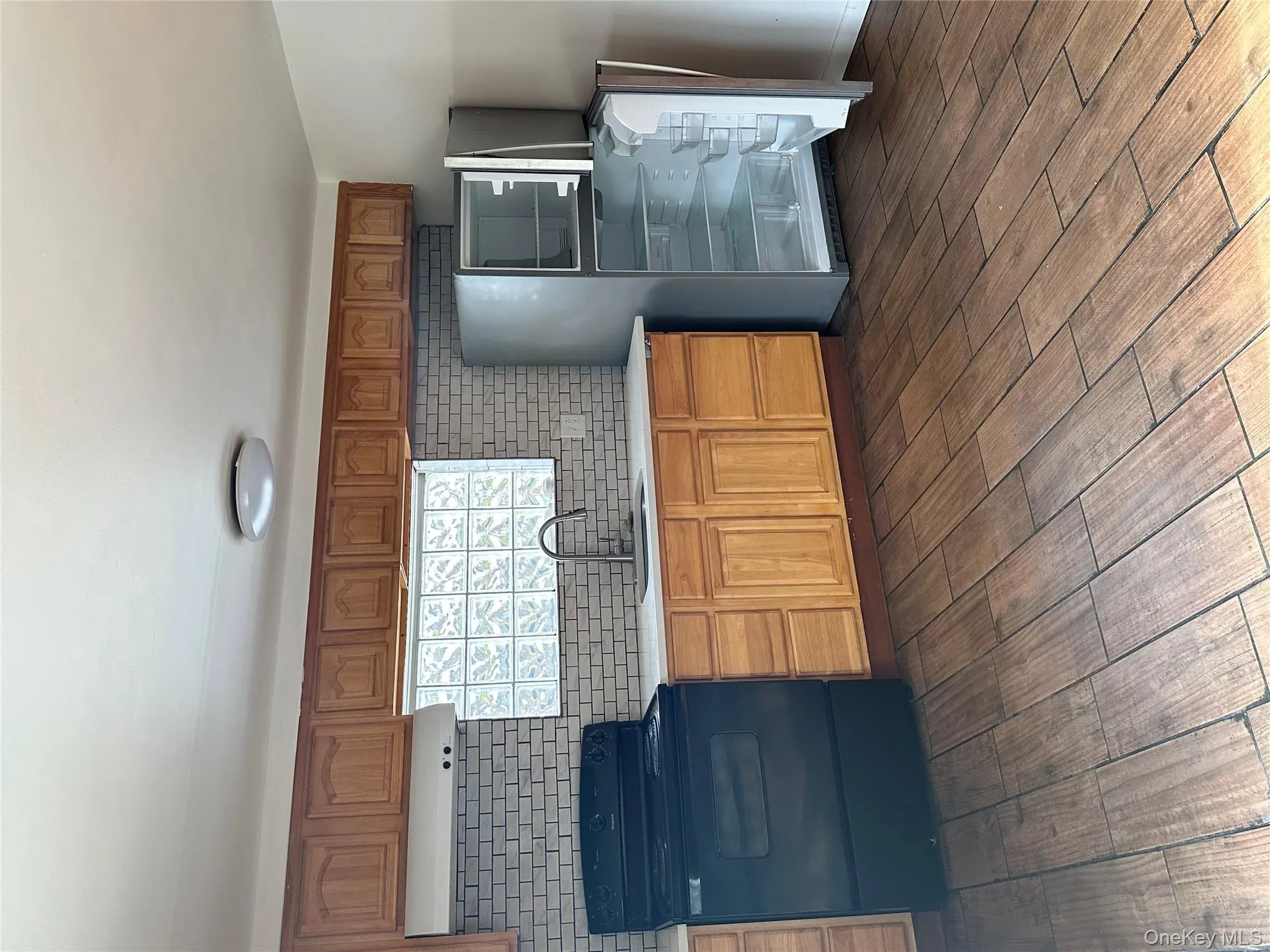 Kitchen with stove, brown cabinets, fridge, extractor fan, and dark wood finished floors Kitchen with stove, brown cabinets, fridge, extractor fan, and dark wood finished floors