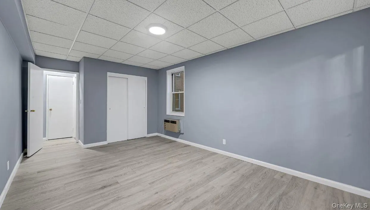 Opposite view of the bedroom featuring wood finished floors, a paneled ceiling, and a closet large enough to fit a king size bed and furniture. Opposite view of the bedroom featuring wood finished floors, a paneled ceiling, and a closet large enough to fit a king size bed and furniture.