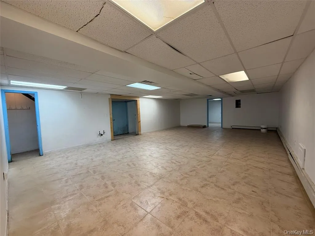 Finished below grade area with a drop ceiling and a baseboard heating unit Finished below grade area with a drop ceiling and a baseboard heating unit