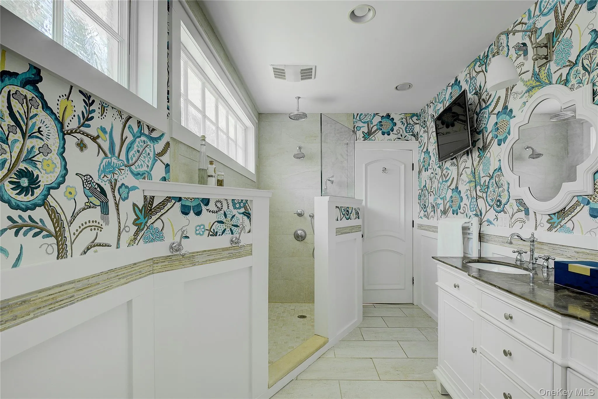 Full bathroom featuring walk in shower, wallpapered walls, vanity, and light tile patterned flooring Full bathroom featuring walk in shower, wallpapered walls, vanity, and light tile patterned flooring