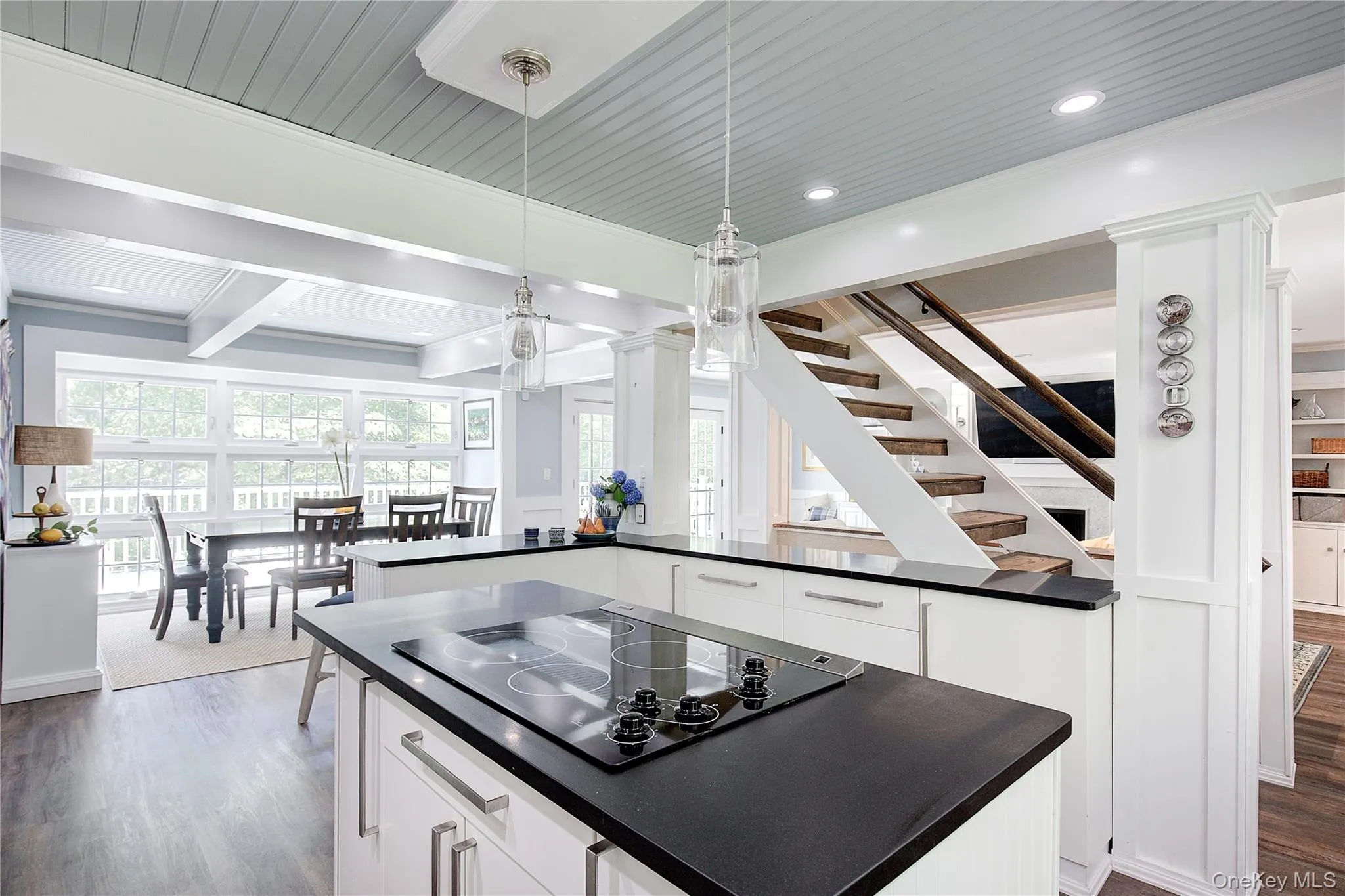 Kitchen with white cabinets, decorative light fixtures, black electric cooktop, dark wood-style floors, and recessed lighting Kitchen with white cabinets, decorative light fixtures, black electric cooktop, dark wood-style floors, and recessed lighting