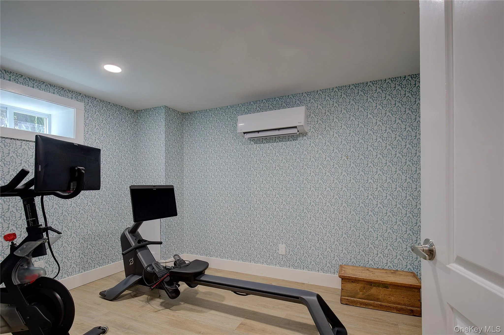 Workout area featuring light wood-style flooring, recessed lighting, an AC wall unit, and wallpapered walls Workout area featuring light wood-style flooring, recessed lighting, an AC wall unit, and wallpapered walls