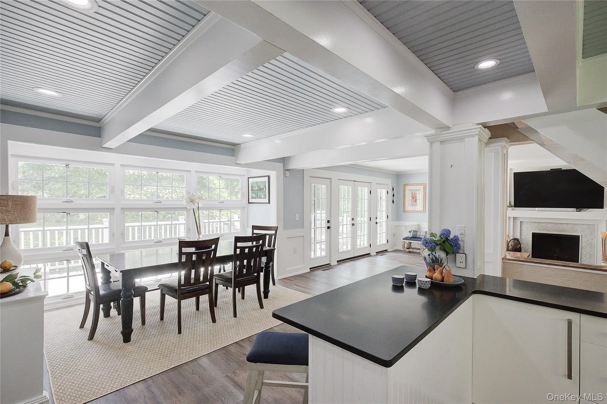 Kitchen featuring beamed ceiling, dark wood-type flooring, wainscoting, french doors, and white cabinetry Kitchen featuring beamed ceiling, dark wood-type flooring, wainscoting, french doors, and white cabinetry