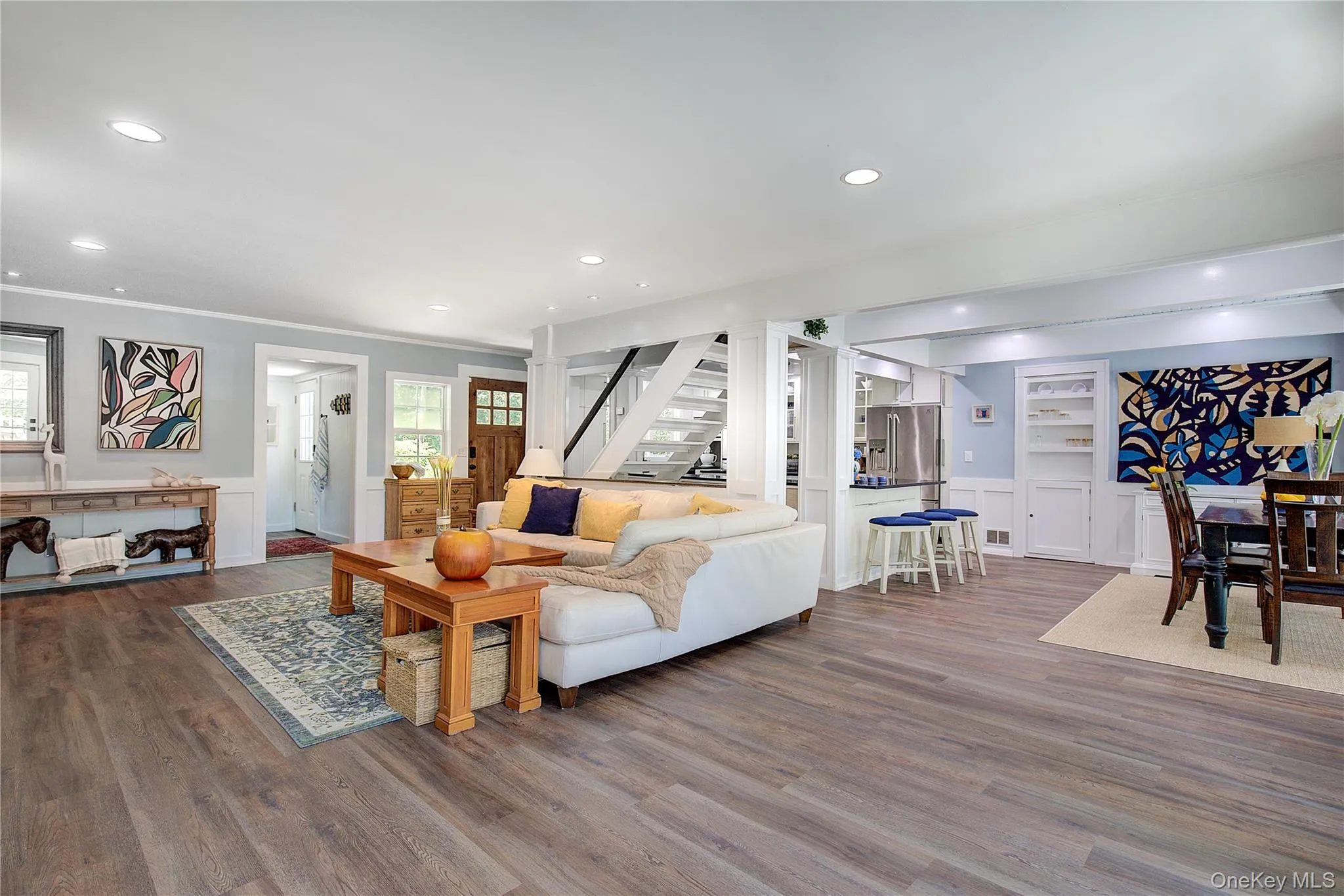 Living room with recessed lighting, wainscoting, stairway, dark wood-style flooring, and healthy amount of natural light Living room with recessed lighting, wainscoting, stairway, dark wood-style flooring, and healthy amount of natural light
